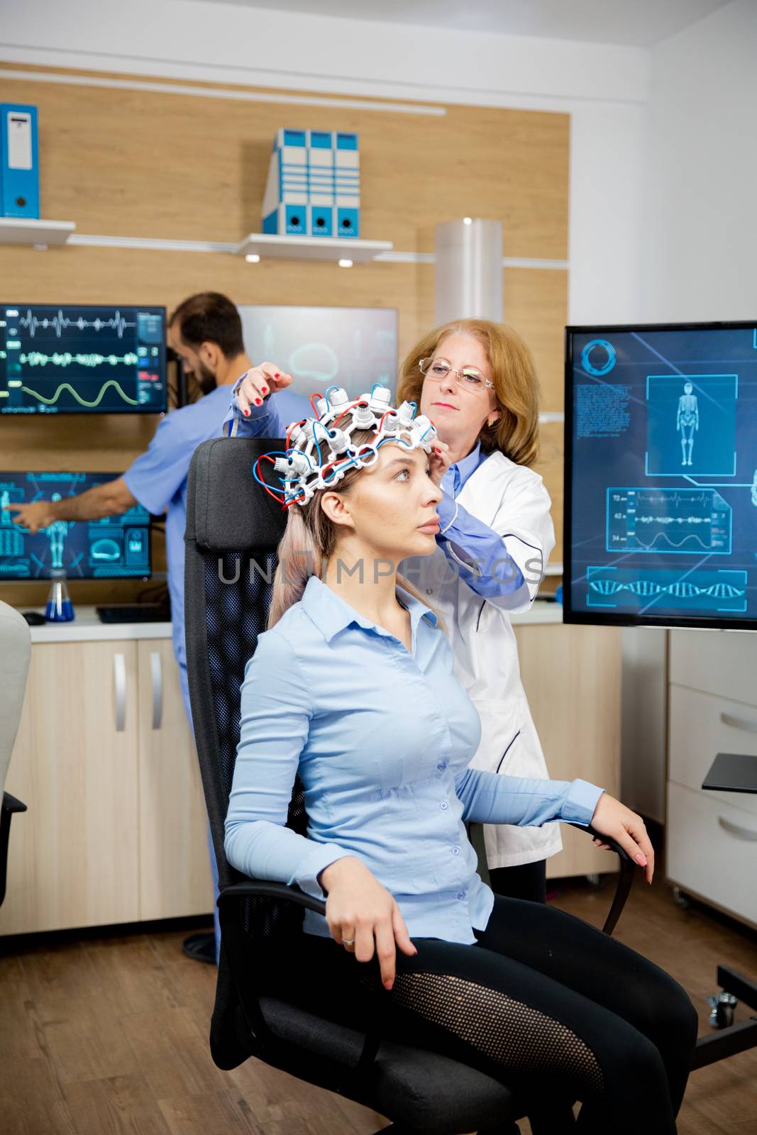 Doctor preparing brain waves scanning headset for tests on a female patient. Clinic experiment