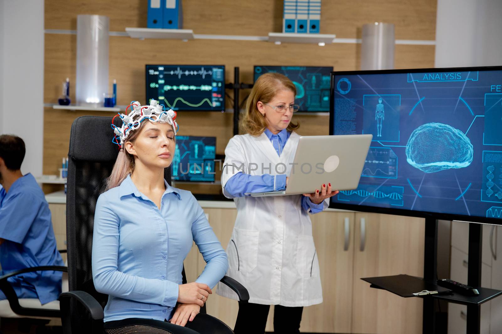 Doctor analyzing live data on a laptop during a girl's brain scan procedure. Brain waves scanning device