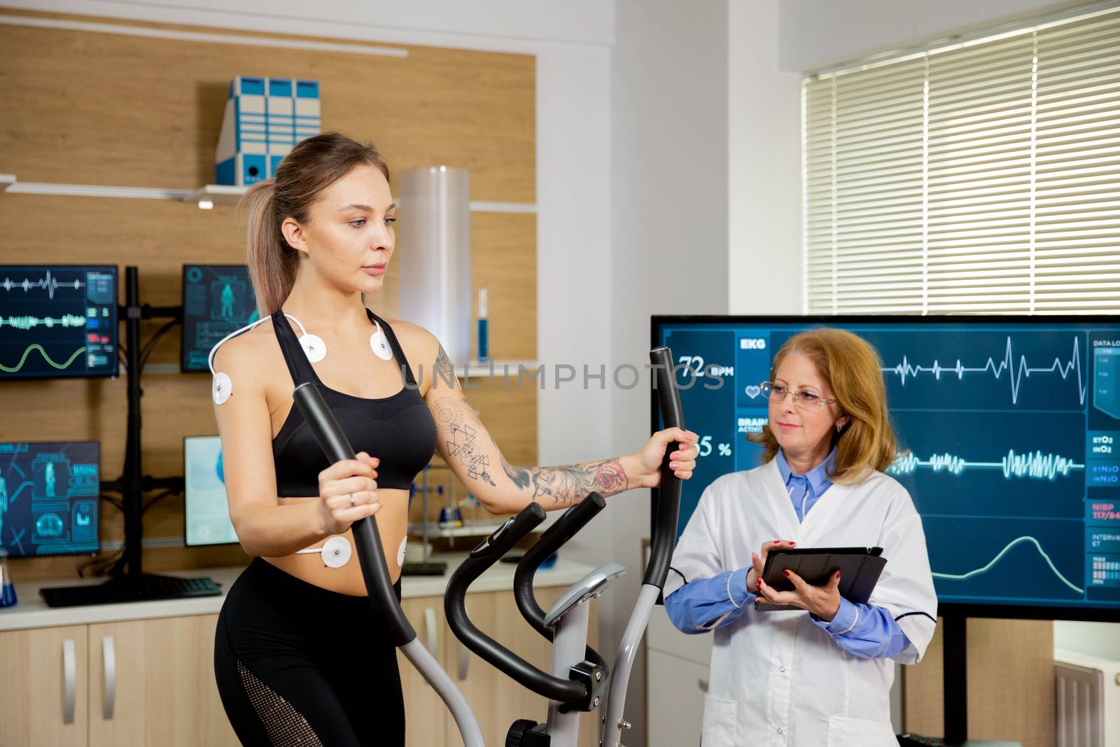 Female athlete who runs tests on the stepper and has electrodes on her and the doctor follows her. Modern sports laboratory