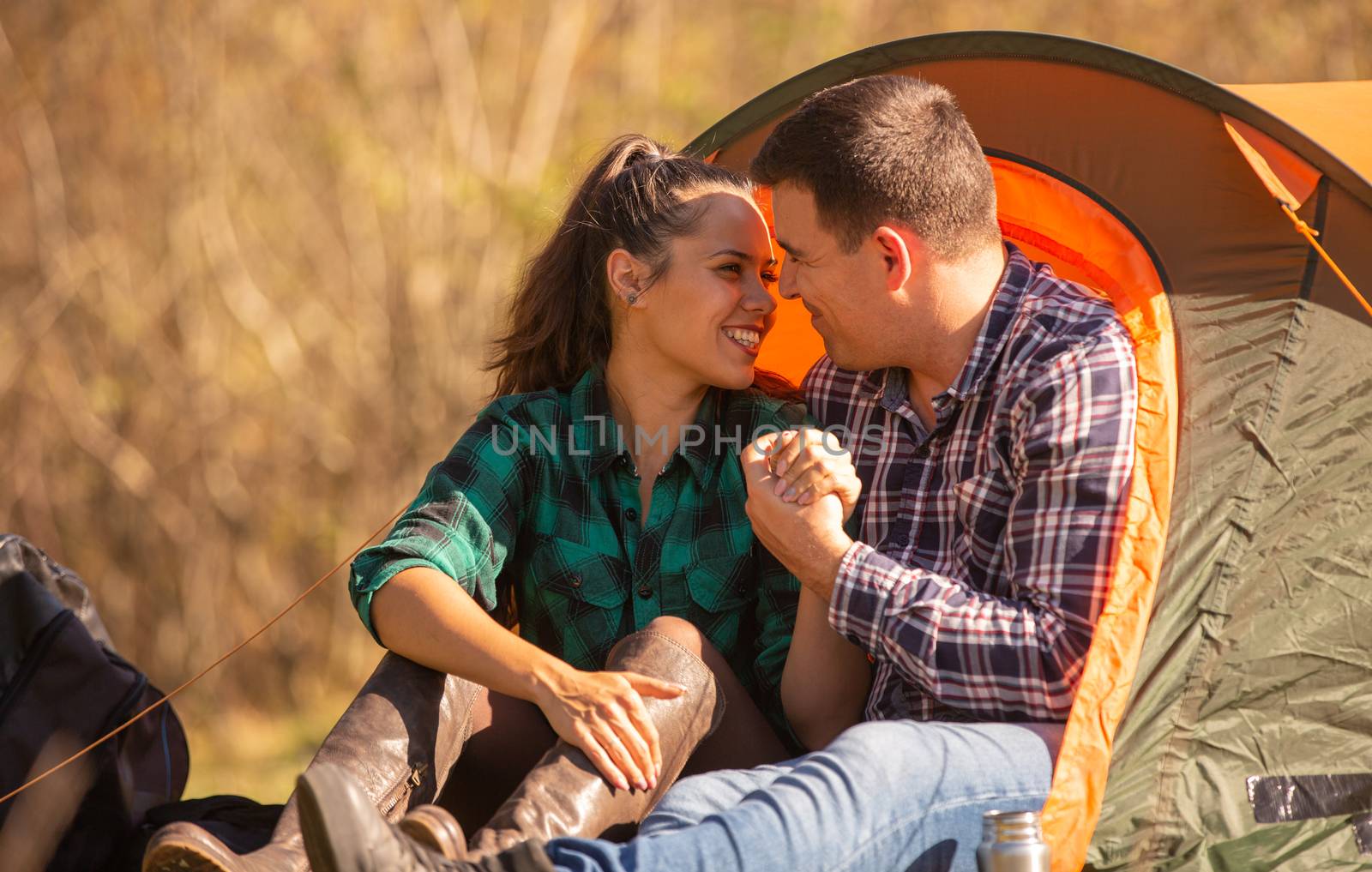 Couple of lovers smiling in front of the tent. Romantic atmosphere