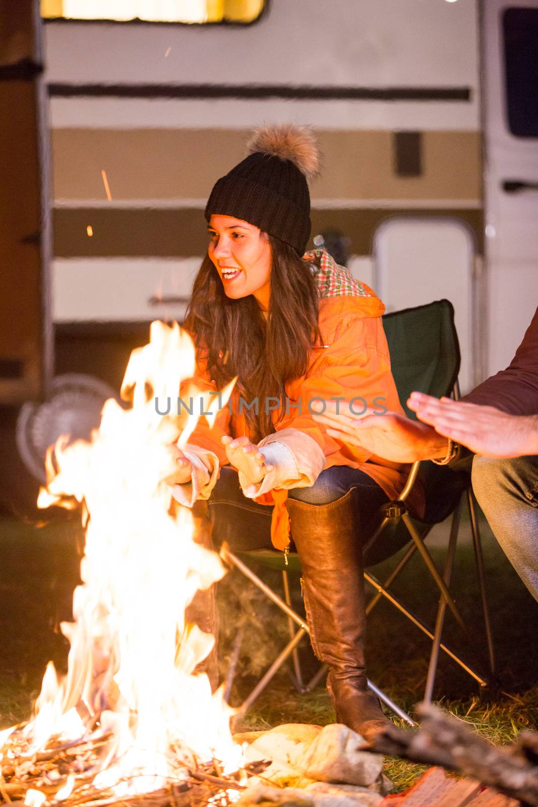 Beautiful young girl laughing and warming around camp fire by DCStudio