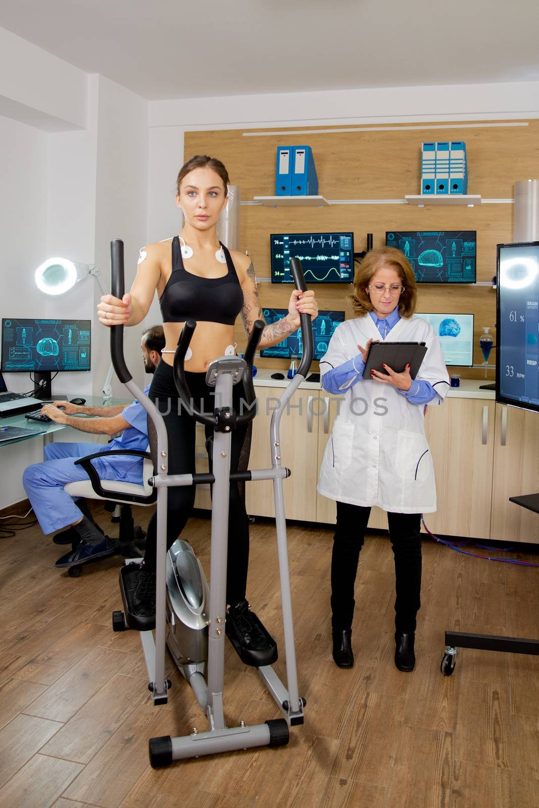 Fit female testing stepper and doctor making notes in tablet. Test with electrodes