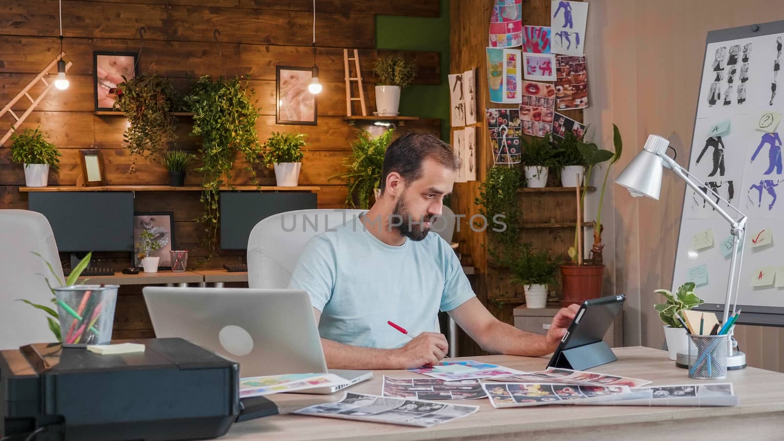 Young designer working on a tablet and making notes. Smart and creative office