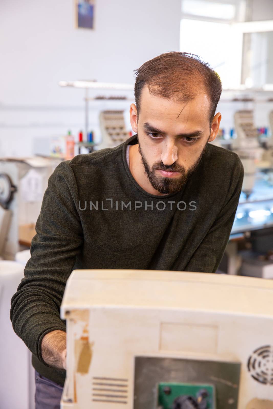 Worker at the textile factory who develops an industrial embroidery machine. Industrial background