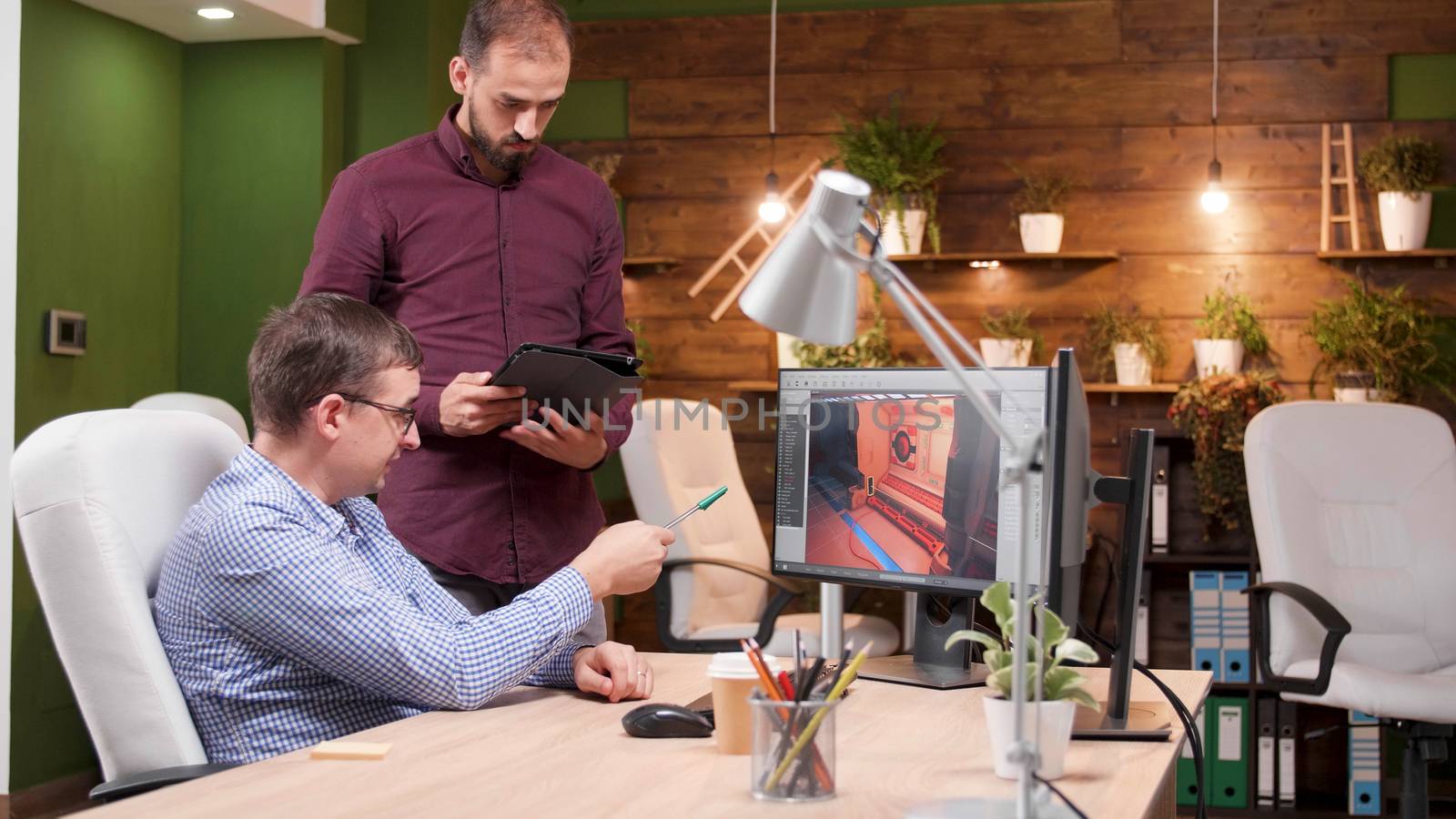 Graphic desginer working in gaming industry showing his assitant the new game design. Game developer.