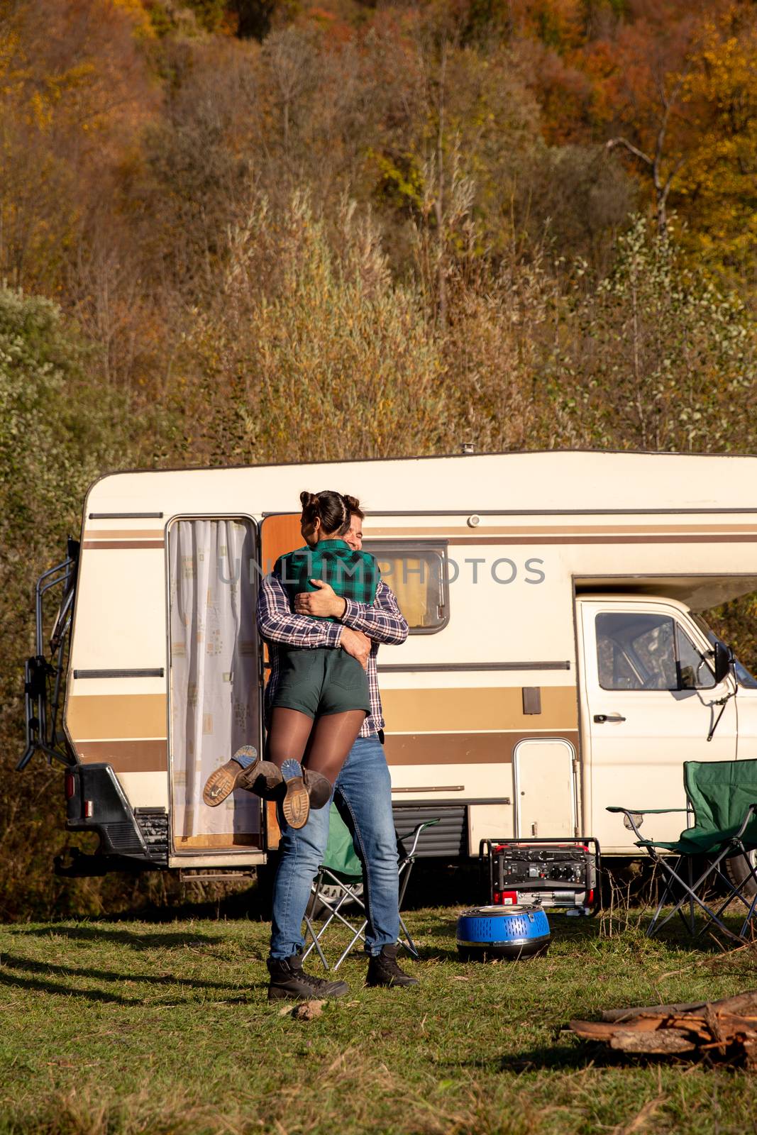 Beautiful young couple having a romantic camping site in the mountains. Retro camper van in the background