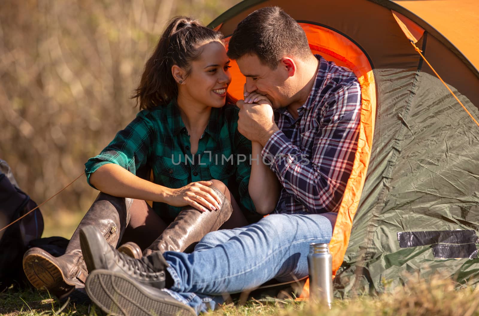 Boyfriend kissing his girlfriend's hand in front of the tent. Happy atmosphere