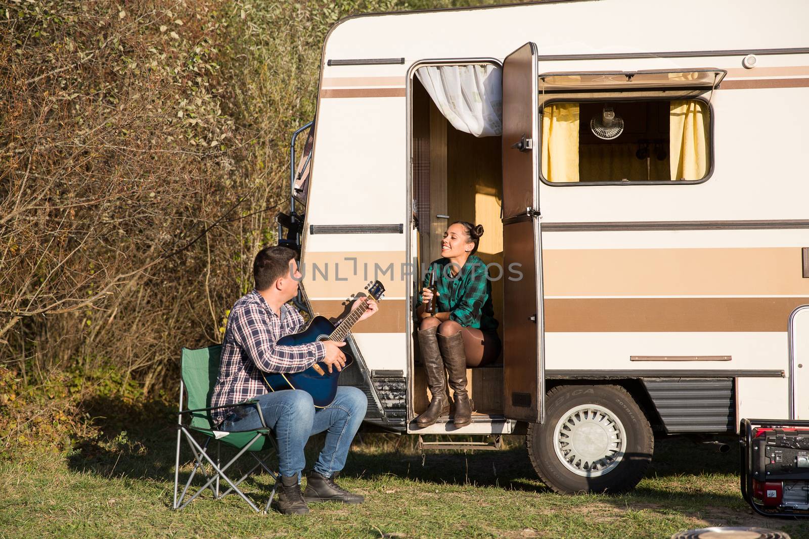 Happy couple enjoying their relationship in the mountains with their retro camper van.