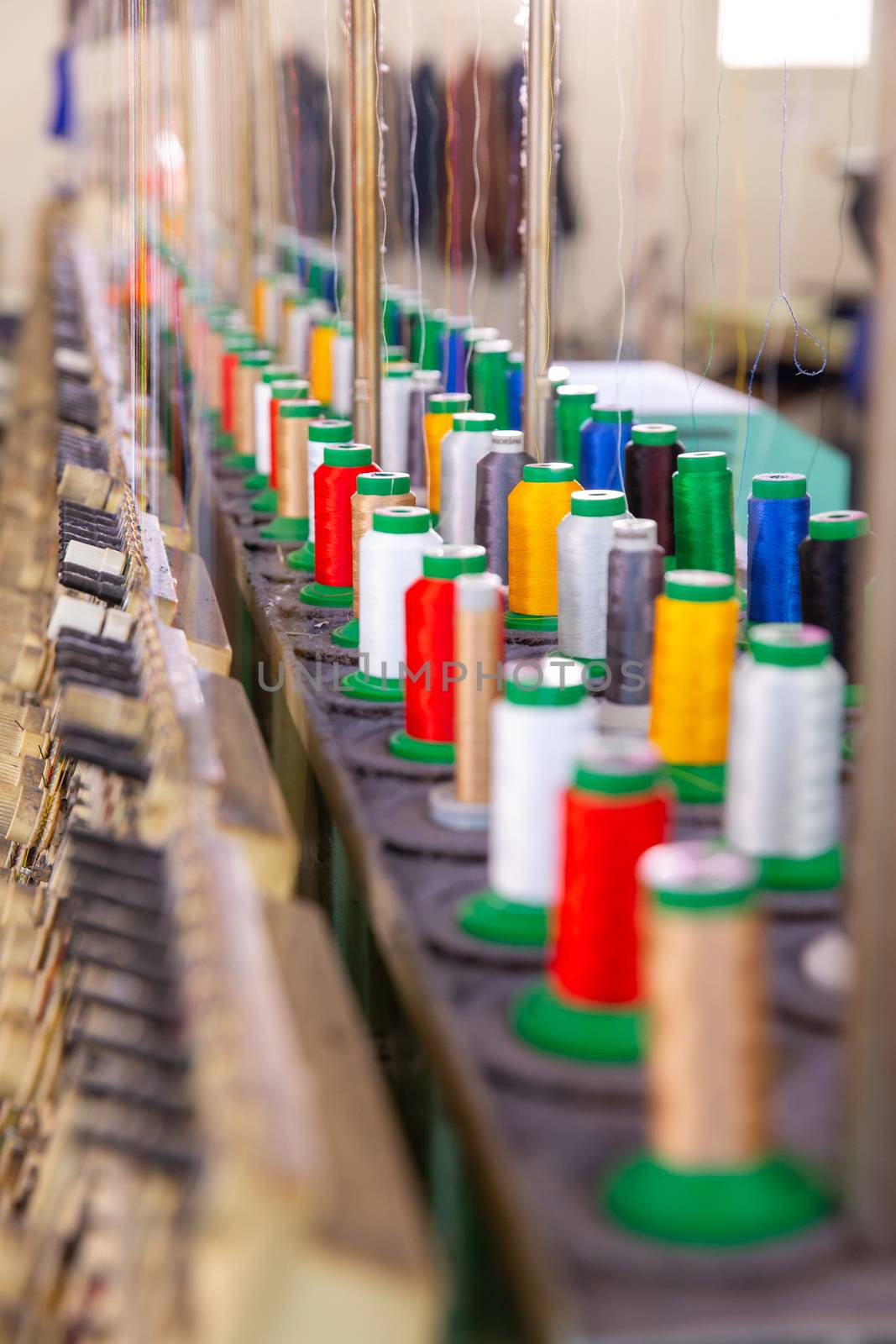 Close up with multicolored spools on an industrial embroidery machine. Tailoring factory