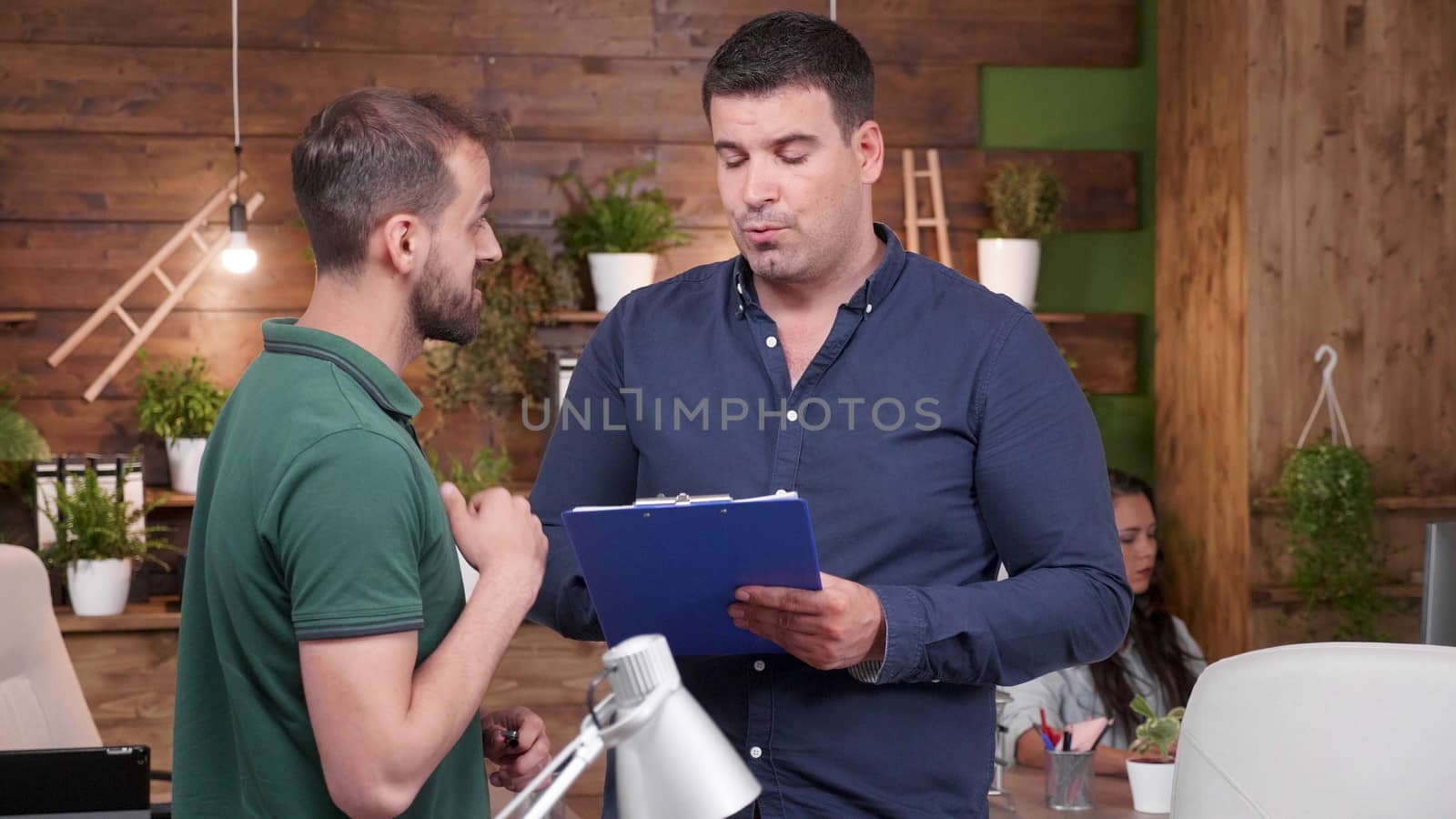 Zoom in portrait of male office working talking with another in cozy office environment. Slow motion footage