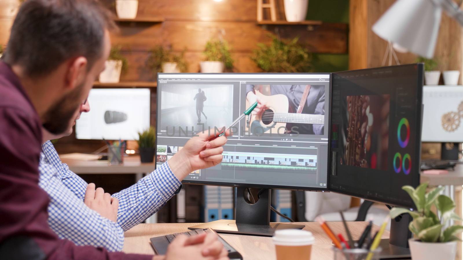 Bearded young videographer in the office talking with his manager. Video editor.