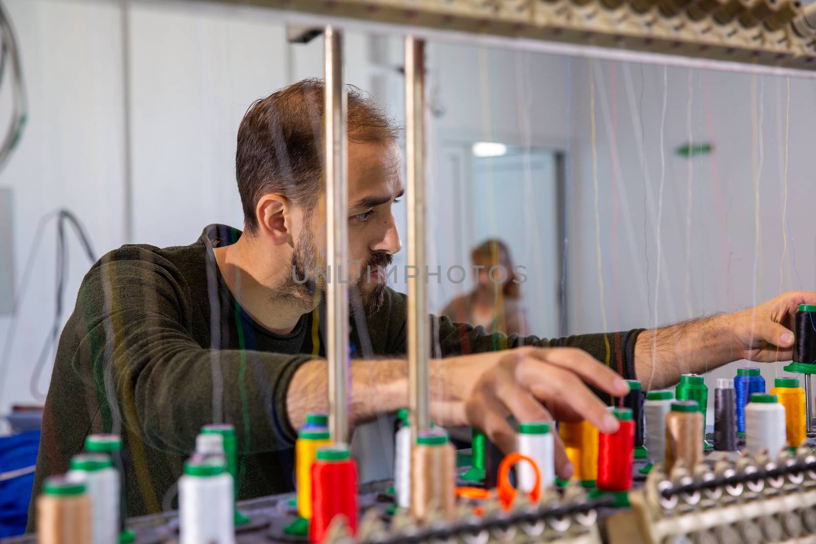 Worker at the sewing factory that arranges the spools of yarn multicolored. Textile production