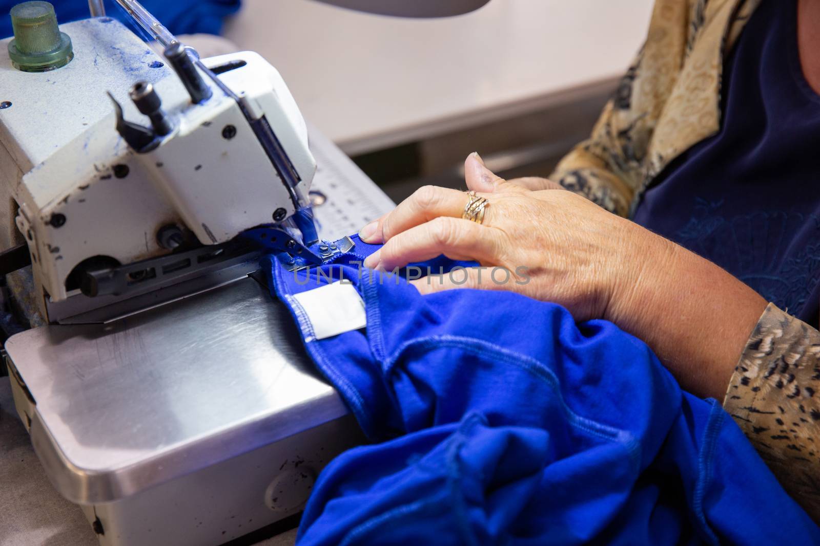 Close up with hands on a seamstress working on a sewing machine. Textile production