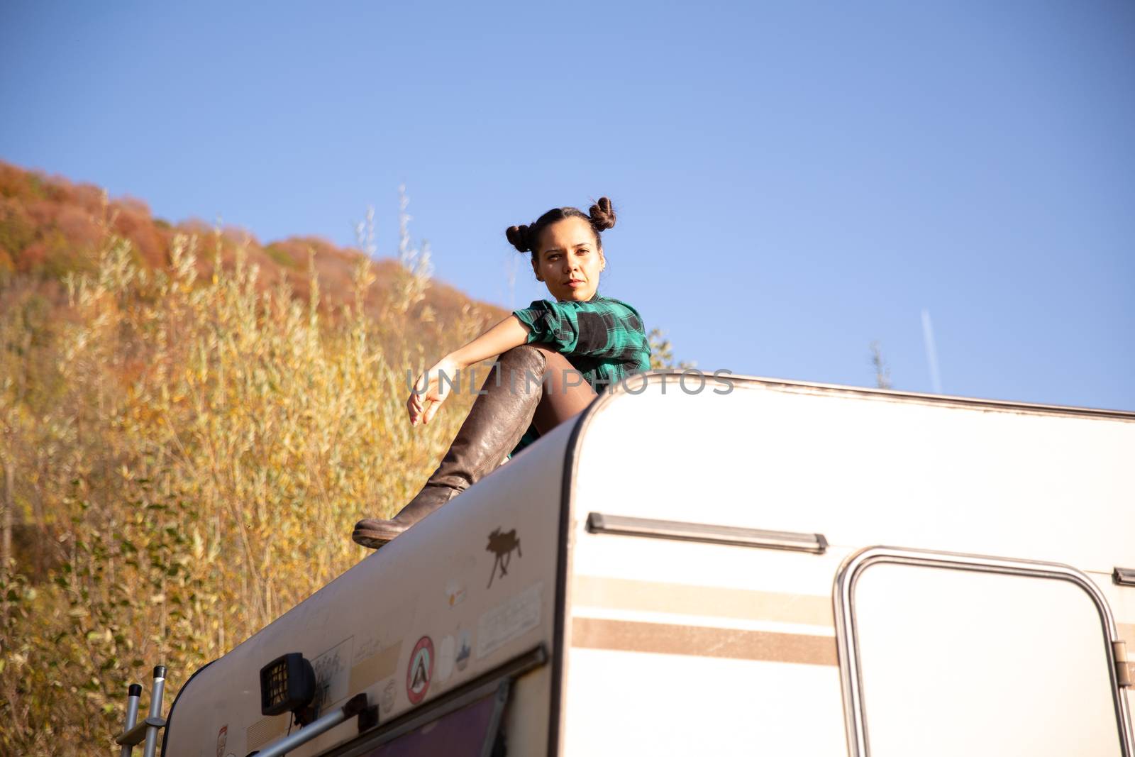 Young girl relaxing on the roof of a retro camper on the mountain. Autumn atmosphere