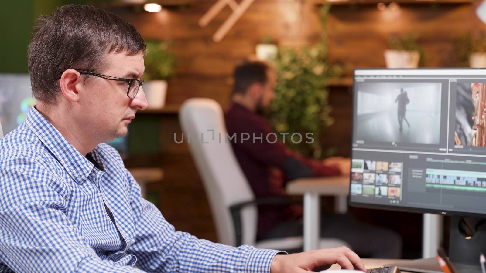 Video editor in the office taking a sip of coffee and working on video post production project.