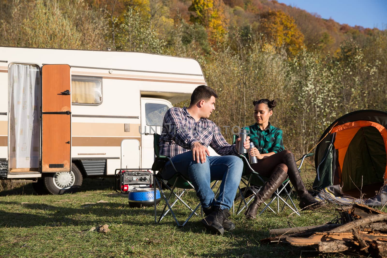 Couple enjoying their holiday in a mountain camps site. Couple camping with retro camper van.