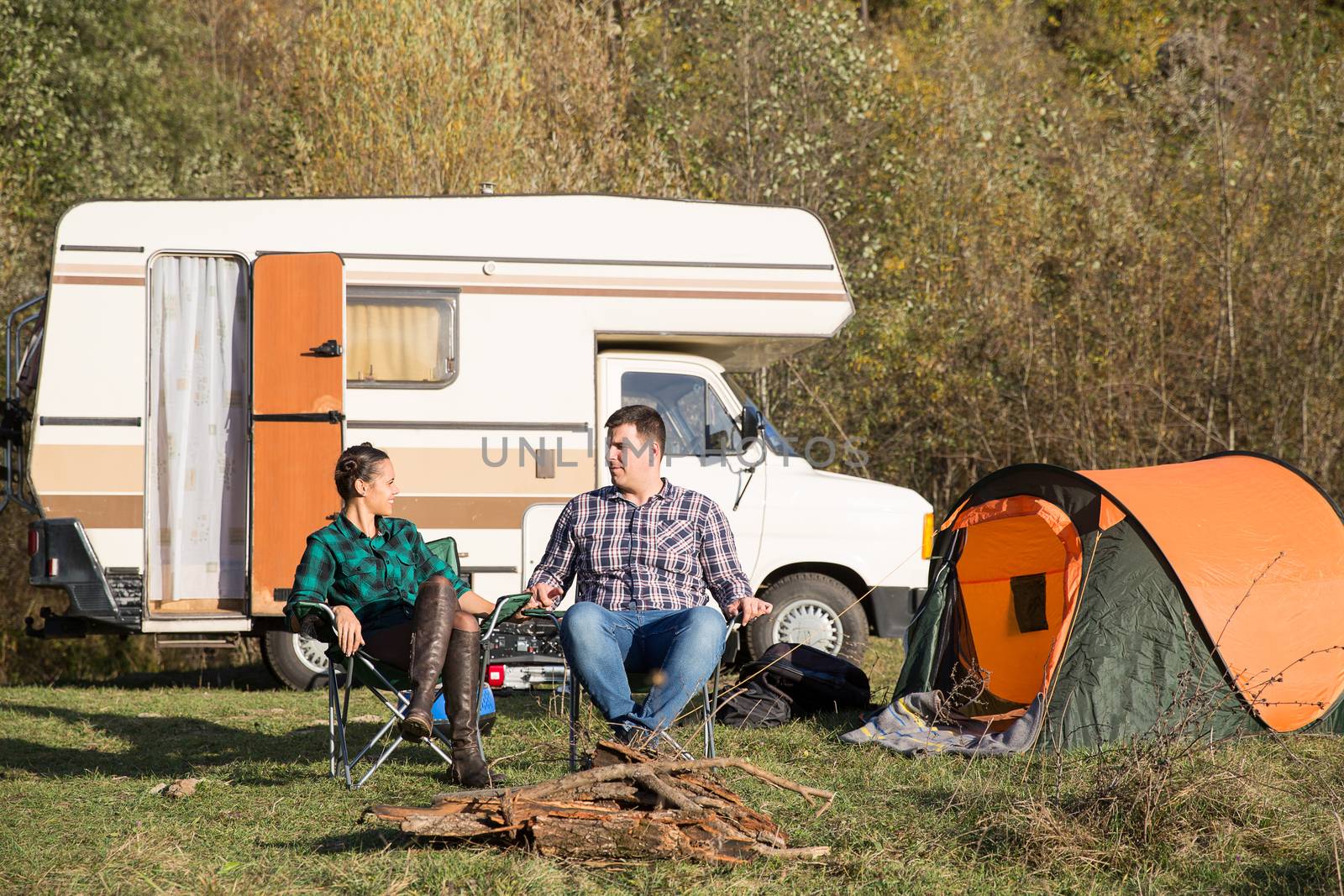 Couple relaxing together in a campsite after an adventure in the mountains. Camping with retro camper van.