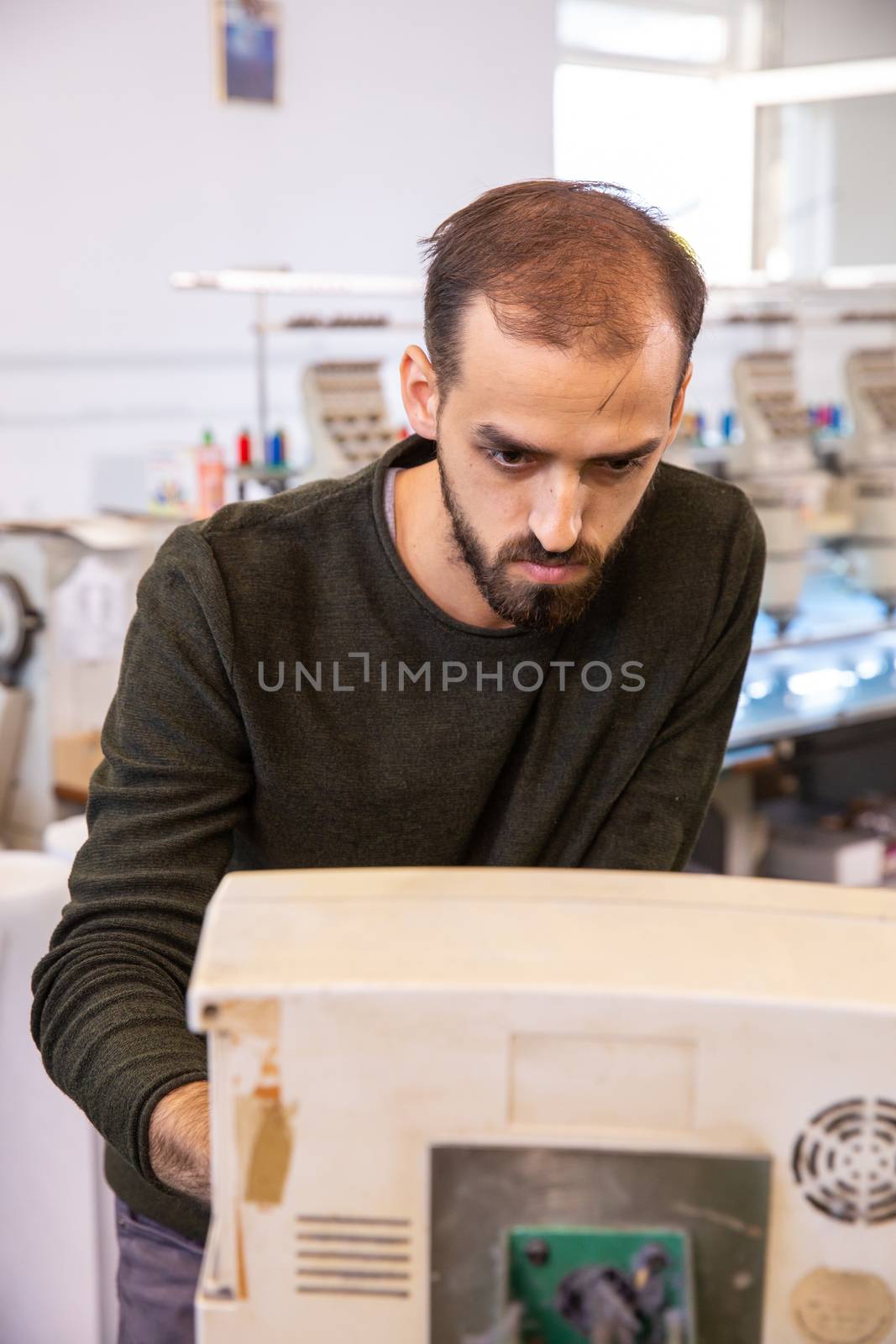 Worker at a textile factory that controls an industrial embroidery machine. Textile industry