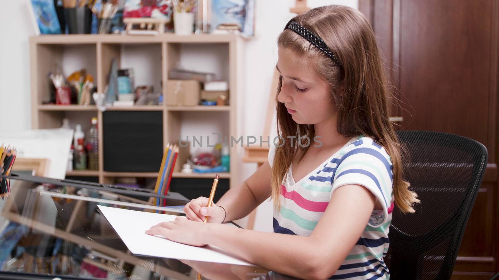 Kid using a protractor and a ruler to draw something on a piece of paper. Preparing for the fine art class.