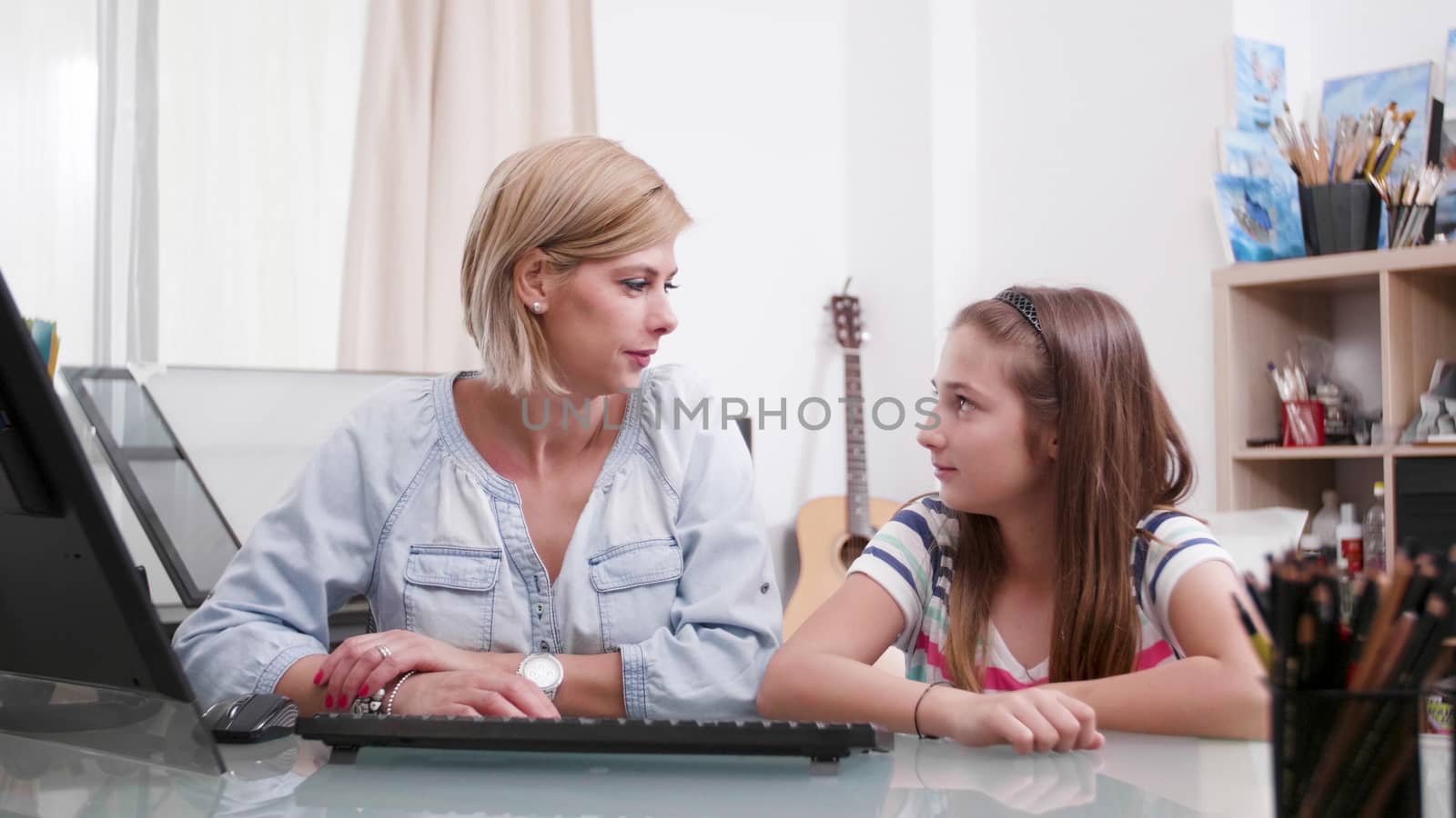 Young beautiful woman looks at her daughter and smiles at her. Female parent and teenage daughter bonding.