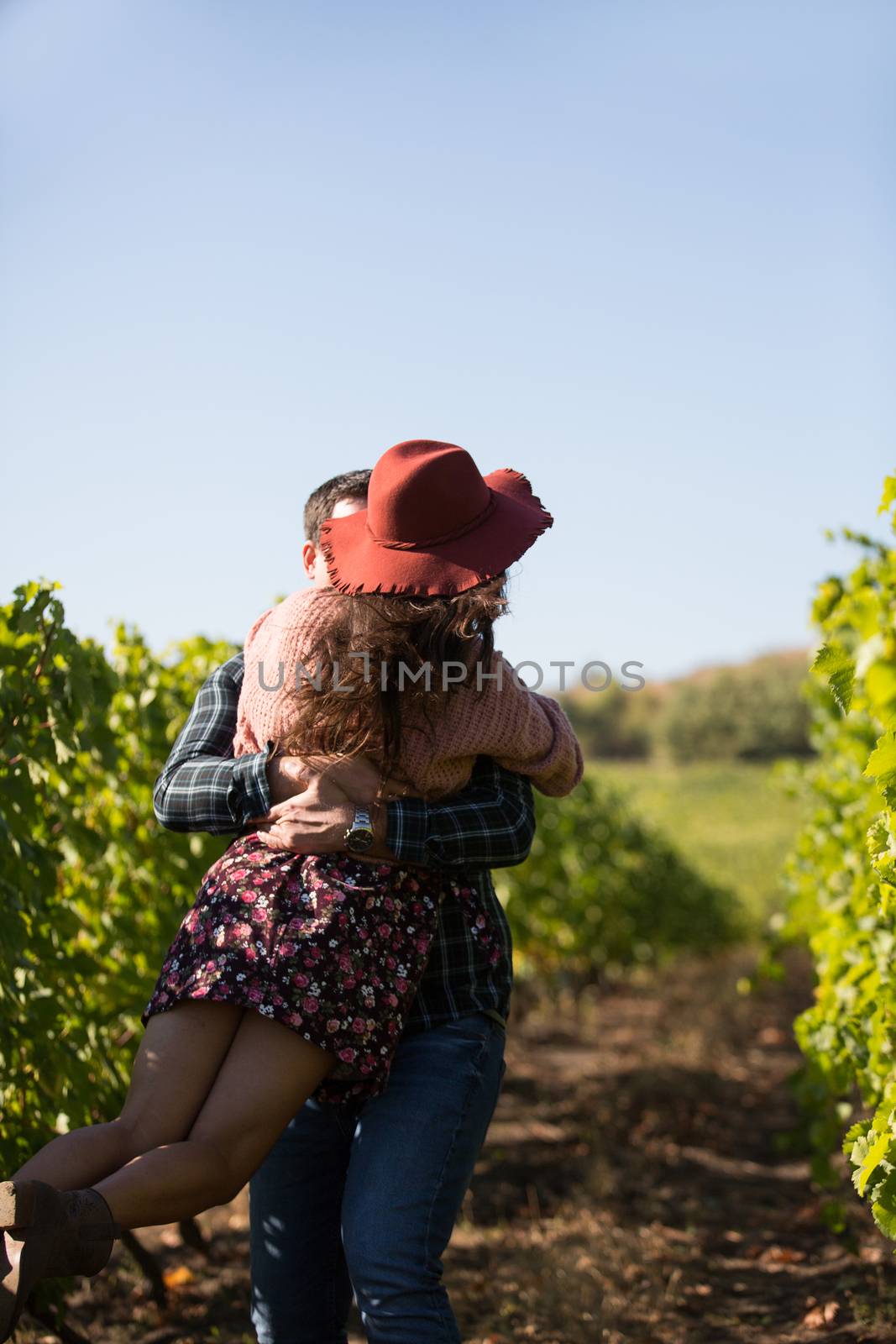 Cheerful young couple having a romantic moment in a vinyard. Woman with stylish hat in vinyard.