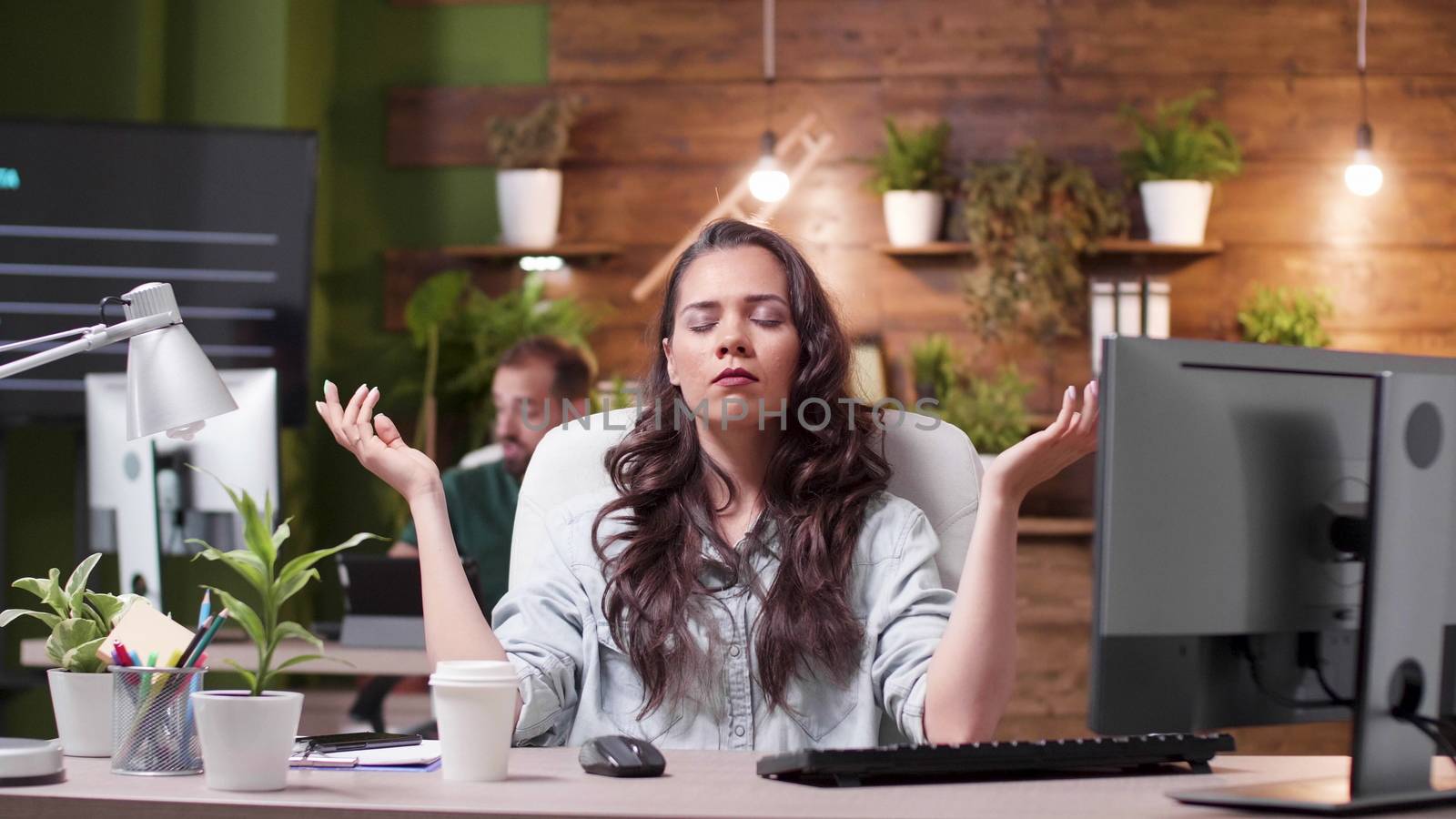 Woman trying to meditate while her colleagues in the background are very stressed by DCStudio