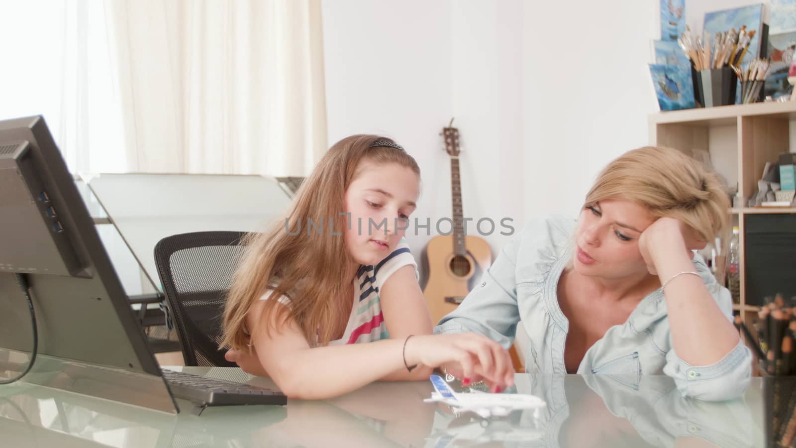 Mother and daughter discussing about their holiday while playing with a toy plane. Dreaming about flying.