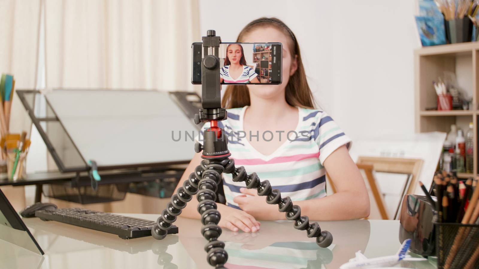Smartphone on a tripod filming a young girl talking. Teenage girl dreams to become a famous vlogger.