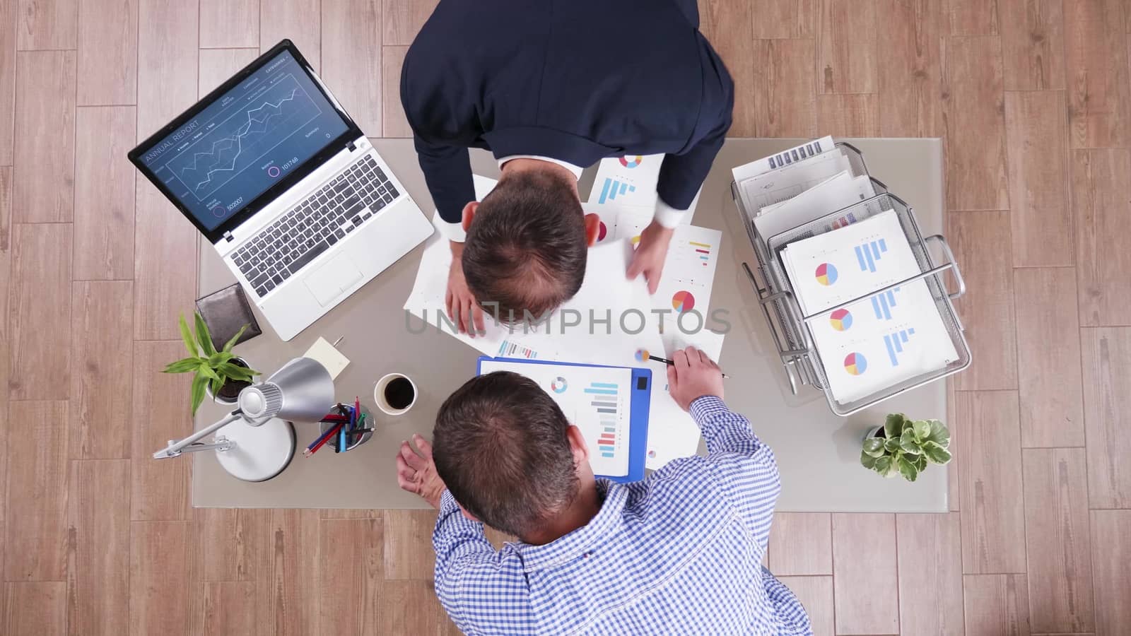 Top view of businessman in his office analysing different charts together with his business advisor.