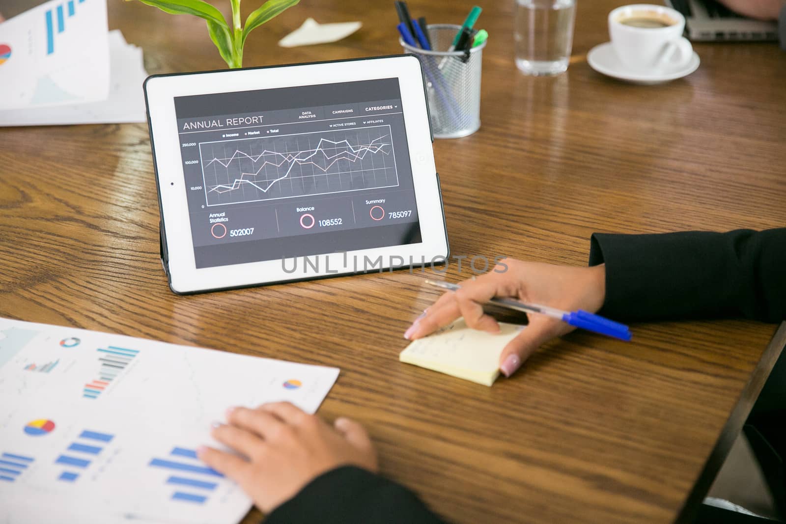 Tablet with charts in the coferene room and business people.