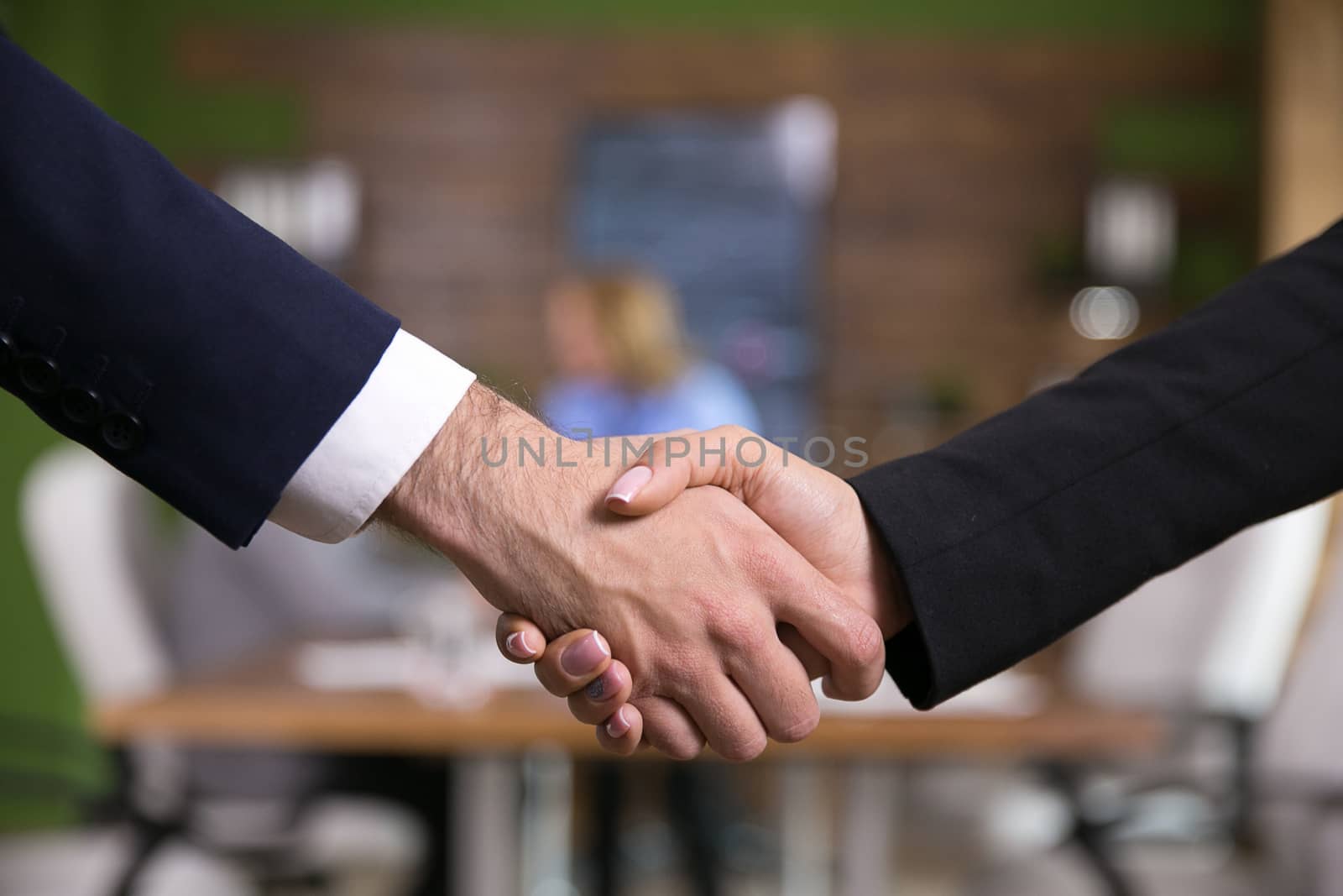 Close up of businessma shaking hands with female entrepreneur in the conference room.