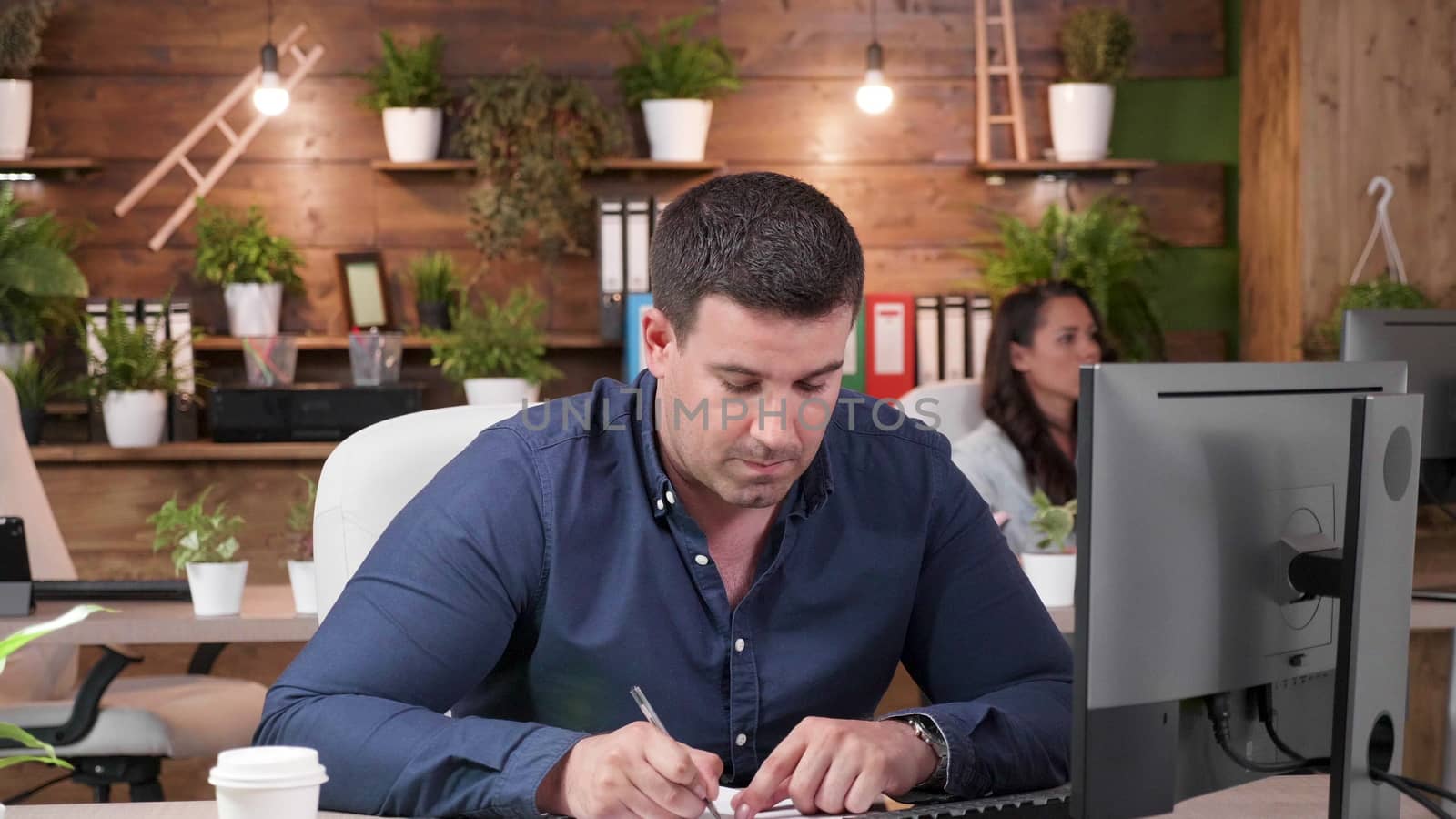 Male office worker taking notes in a busy day at the work. Slow motion zoom in shot