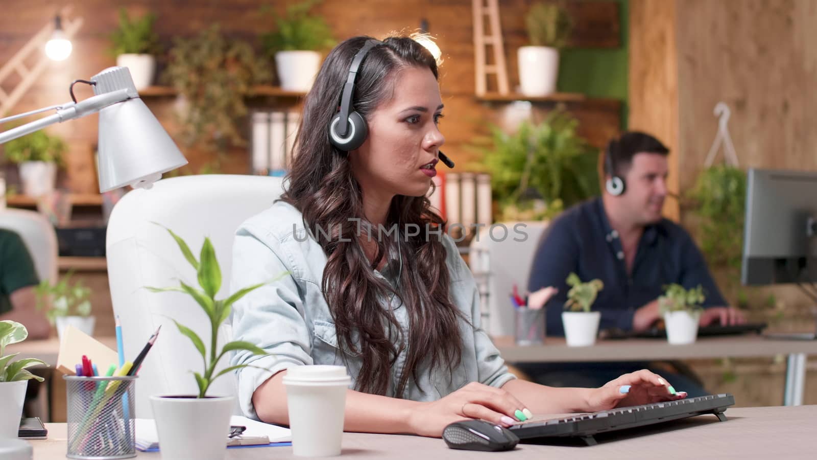 Customer support operators are working in cozy office. Beautiful woman talks using the headsets