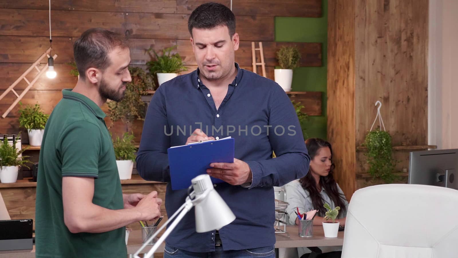 Two male colleagues standing and talking in modern cozy office. Slow motion zoom in shot
