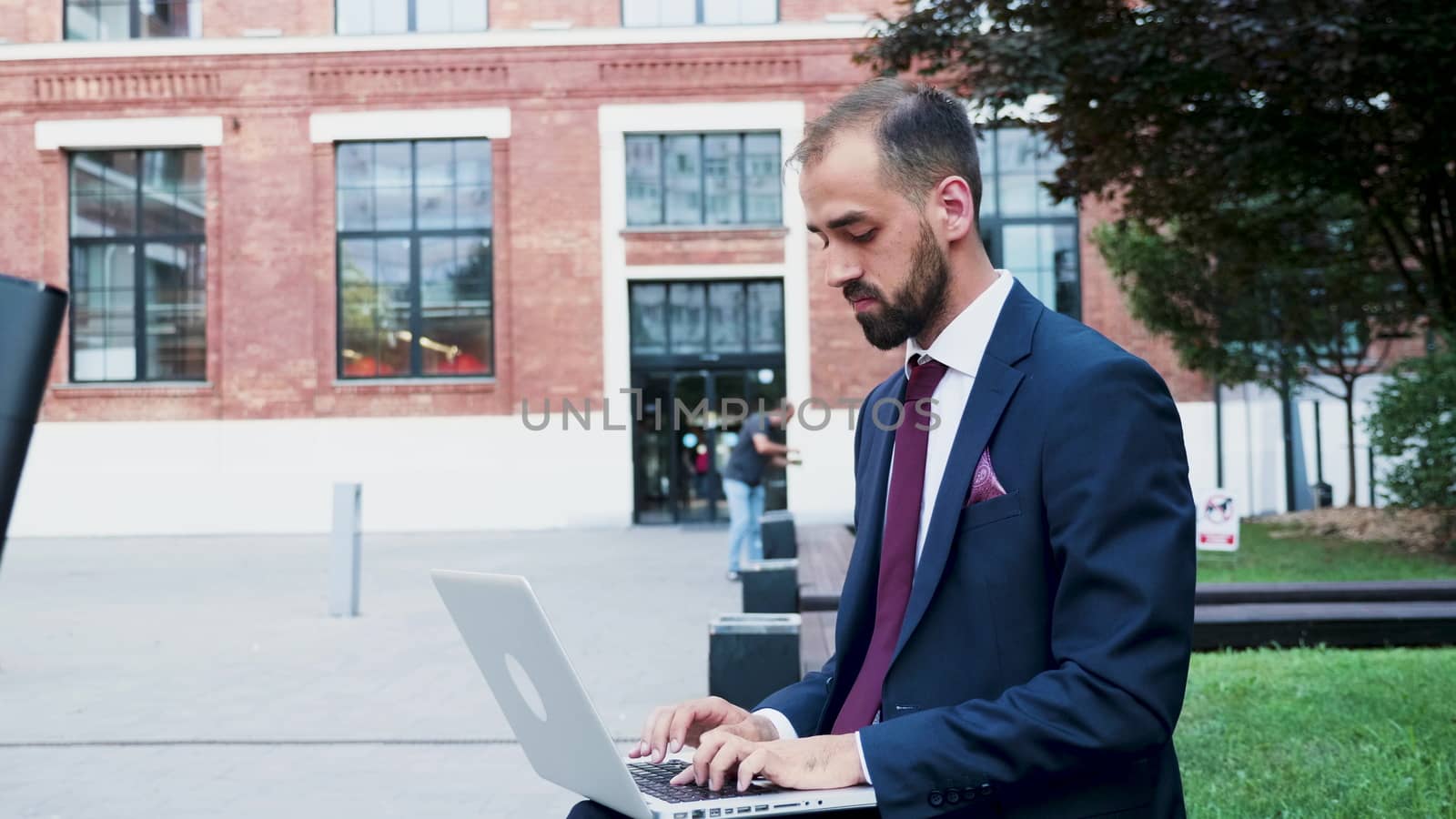 Young businessman working on the laptop in a business district, close up slow motion. Business on the go