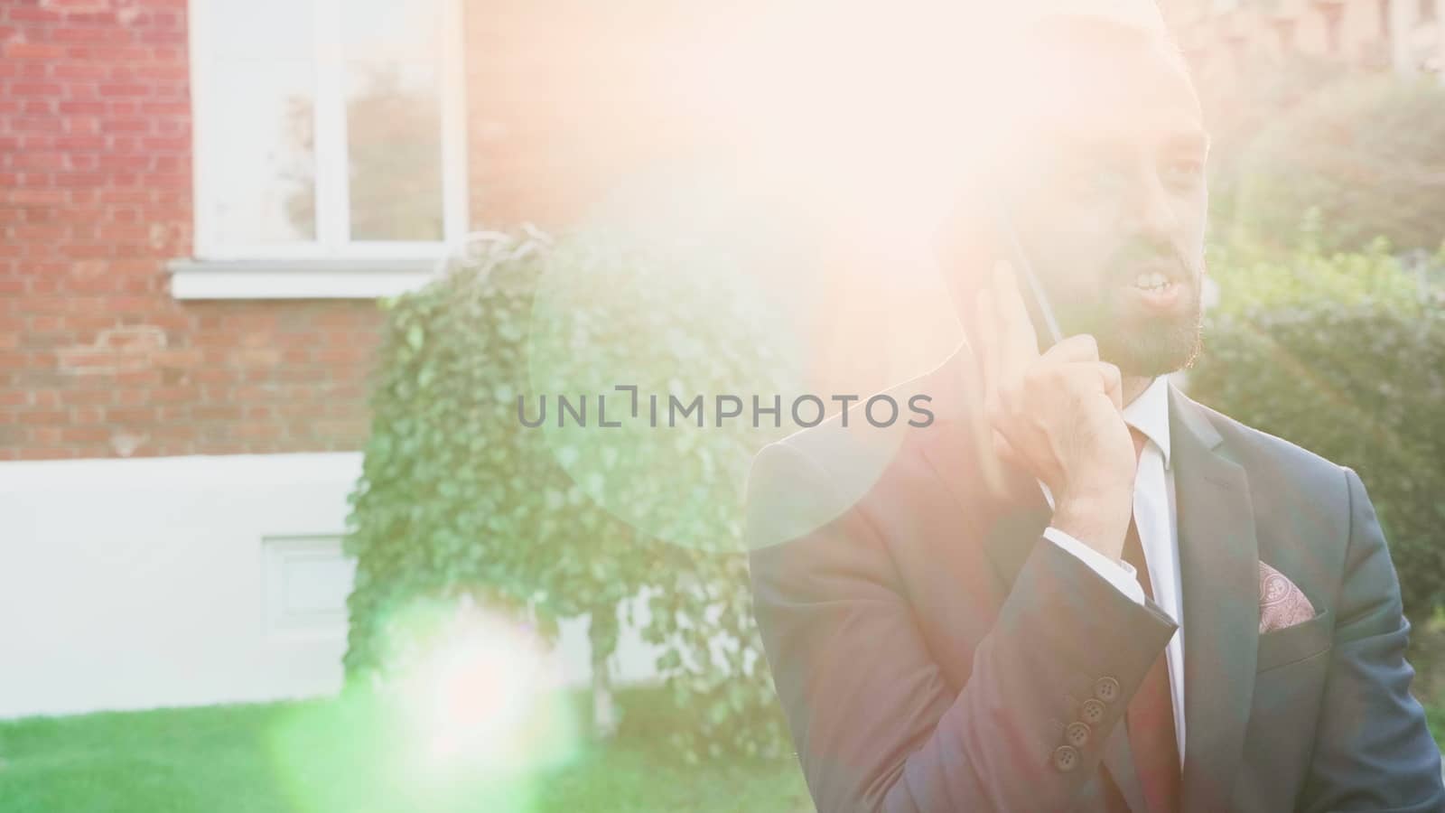 Manager in business suit having a conversation on the phone in the city. Beautiful lens flares from behind. Slow motion shot