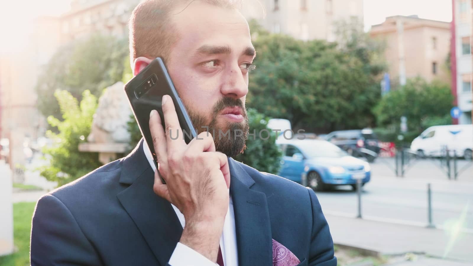 Portrait of young businessman talking on the phone in lens flares, selective soft focus shot. Slow motion footage