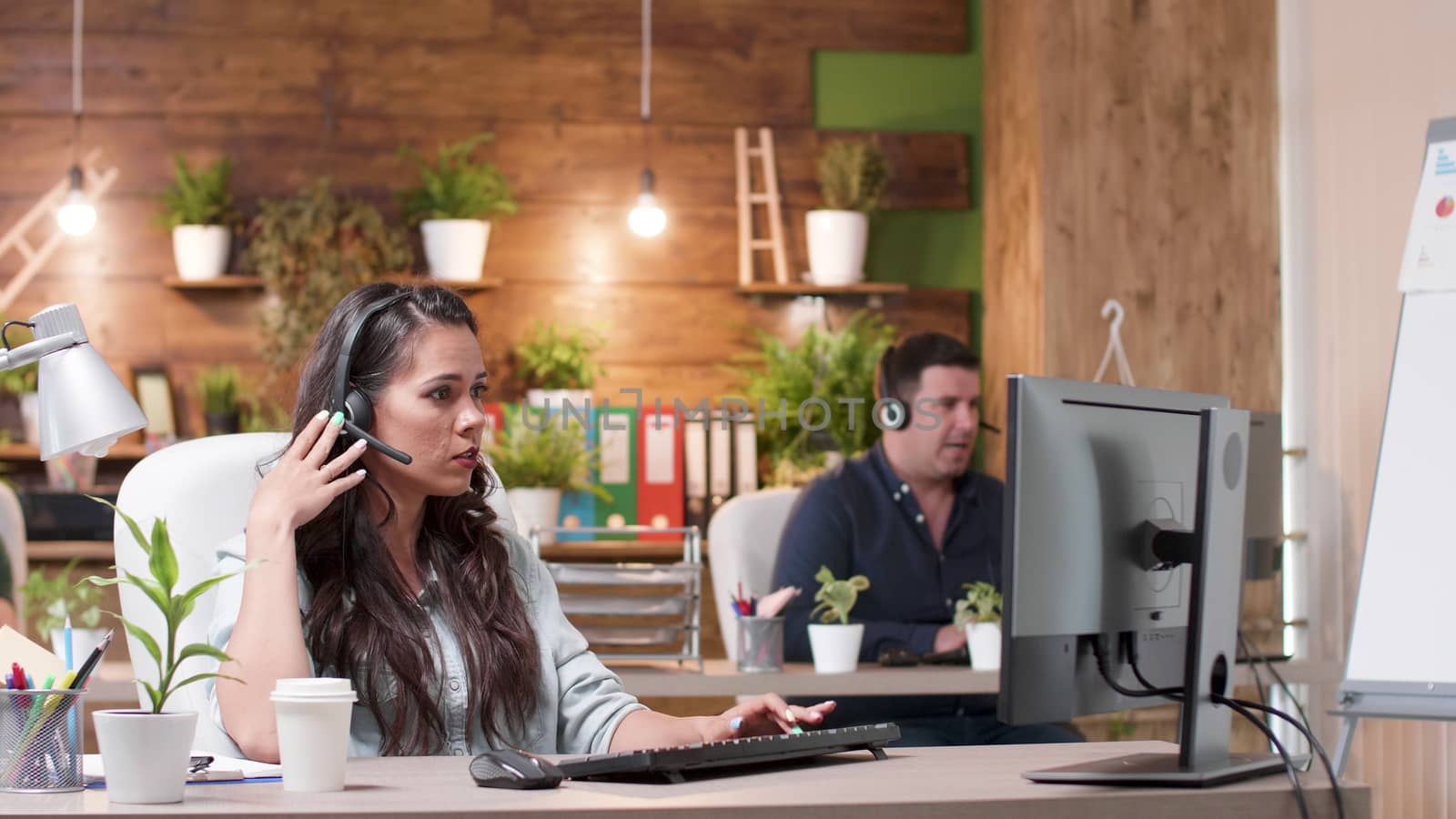 Customer service or sales operators working in a cozy office. Wide dolly shot