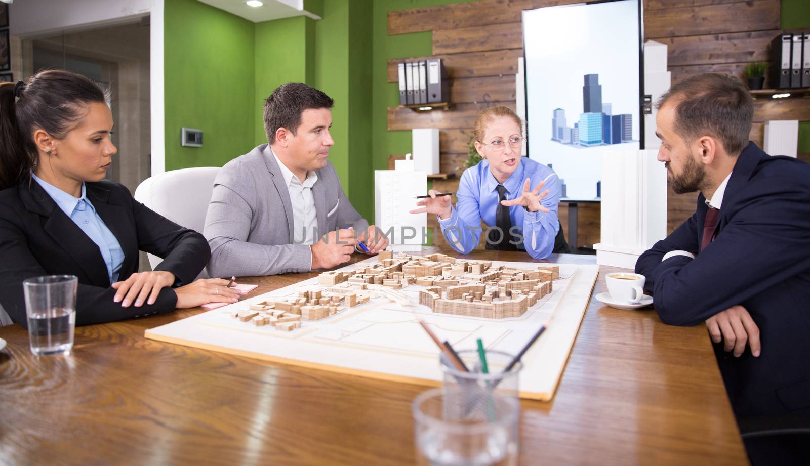 Middle age real estate developer in a meeting with construction engineers. Mini town. Building model.