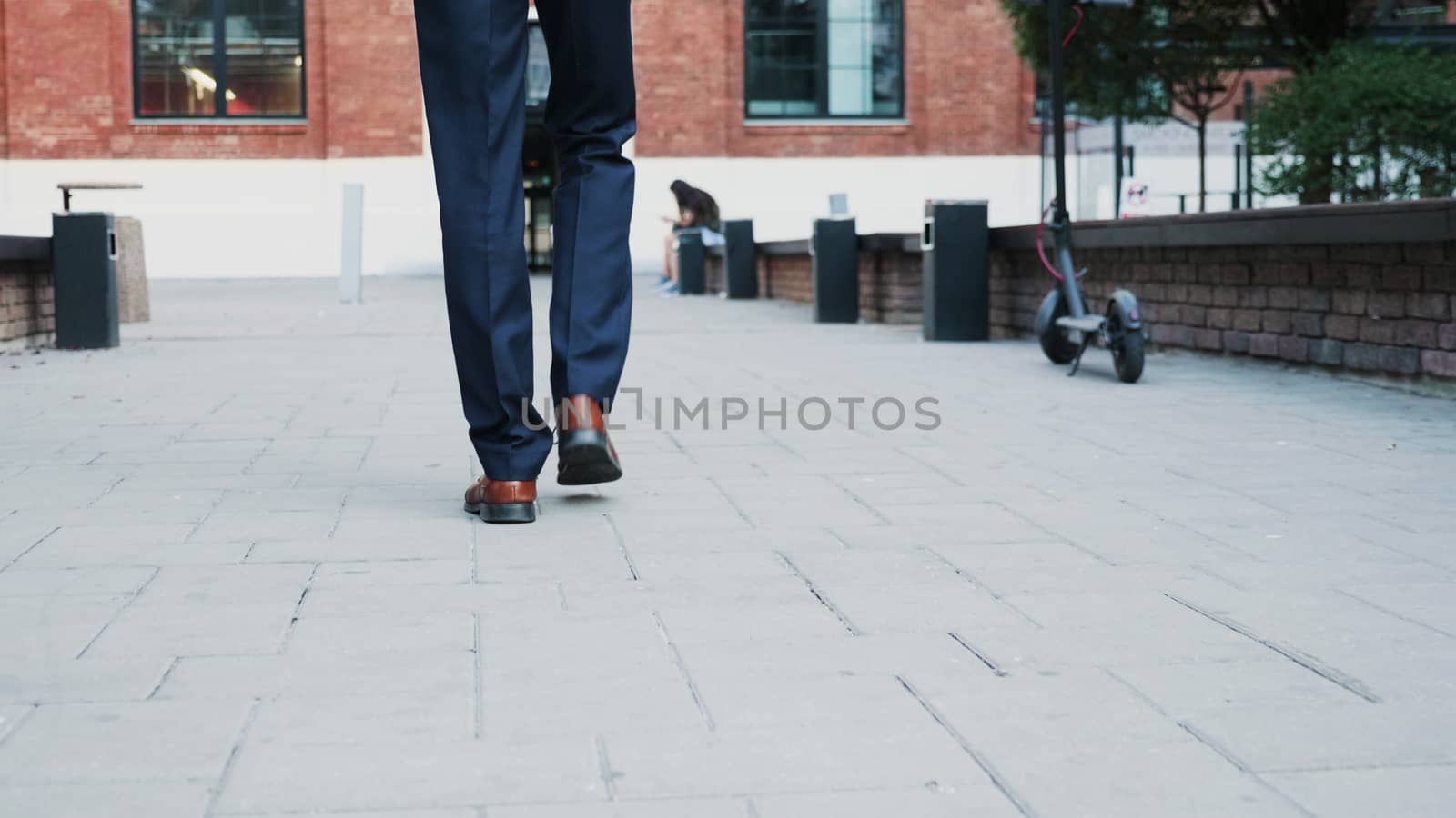 Unrecognisable businessman feet walking in the business district, back view tracking shot