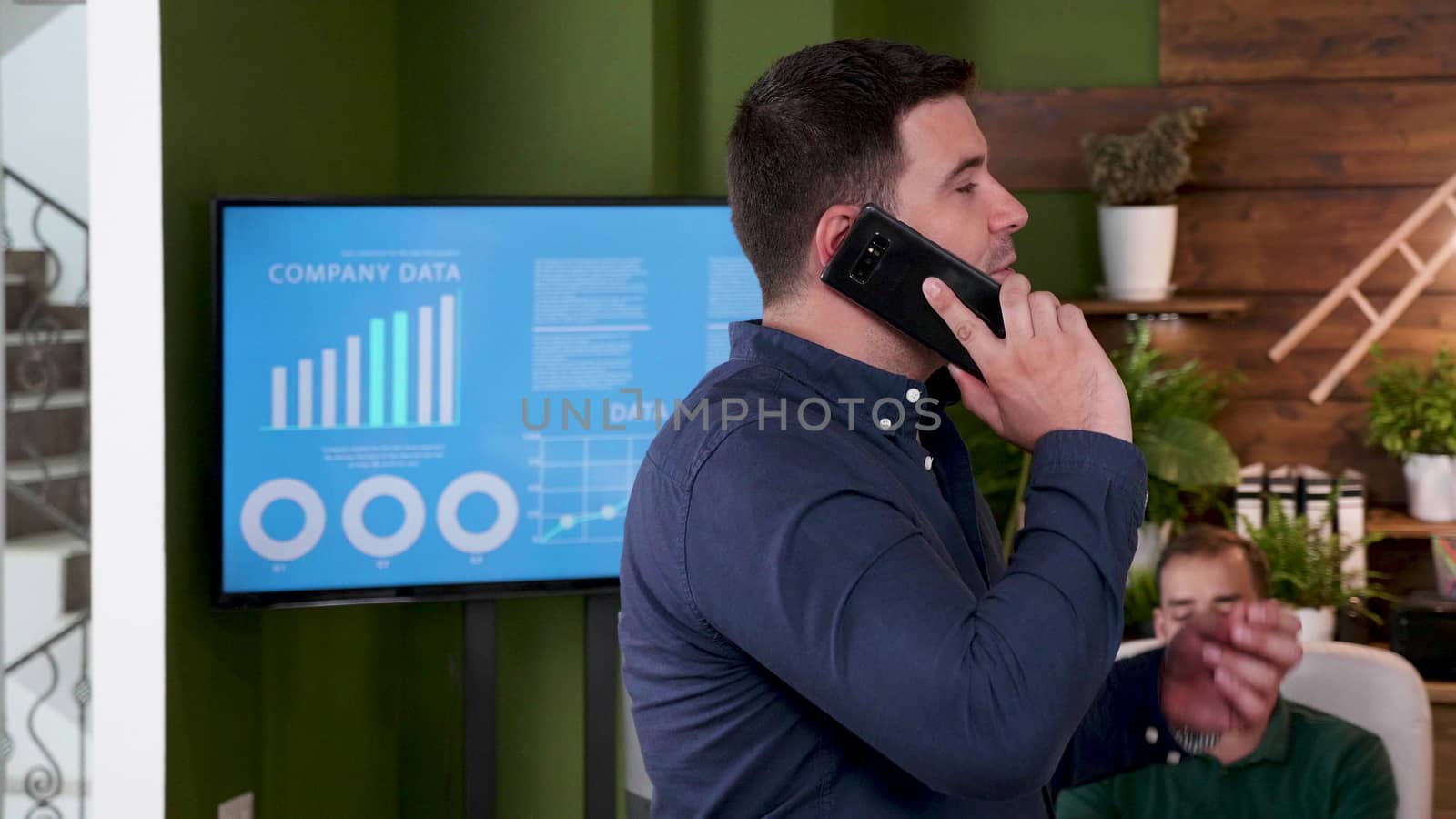 Businessman talks on the phone while walking in the office. Slow motion shot