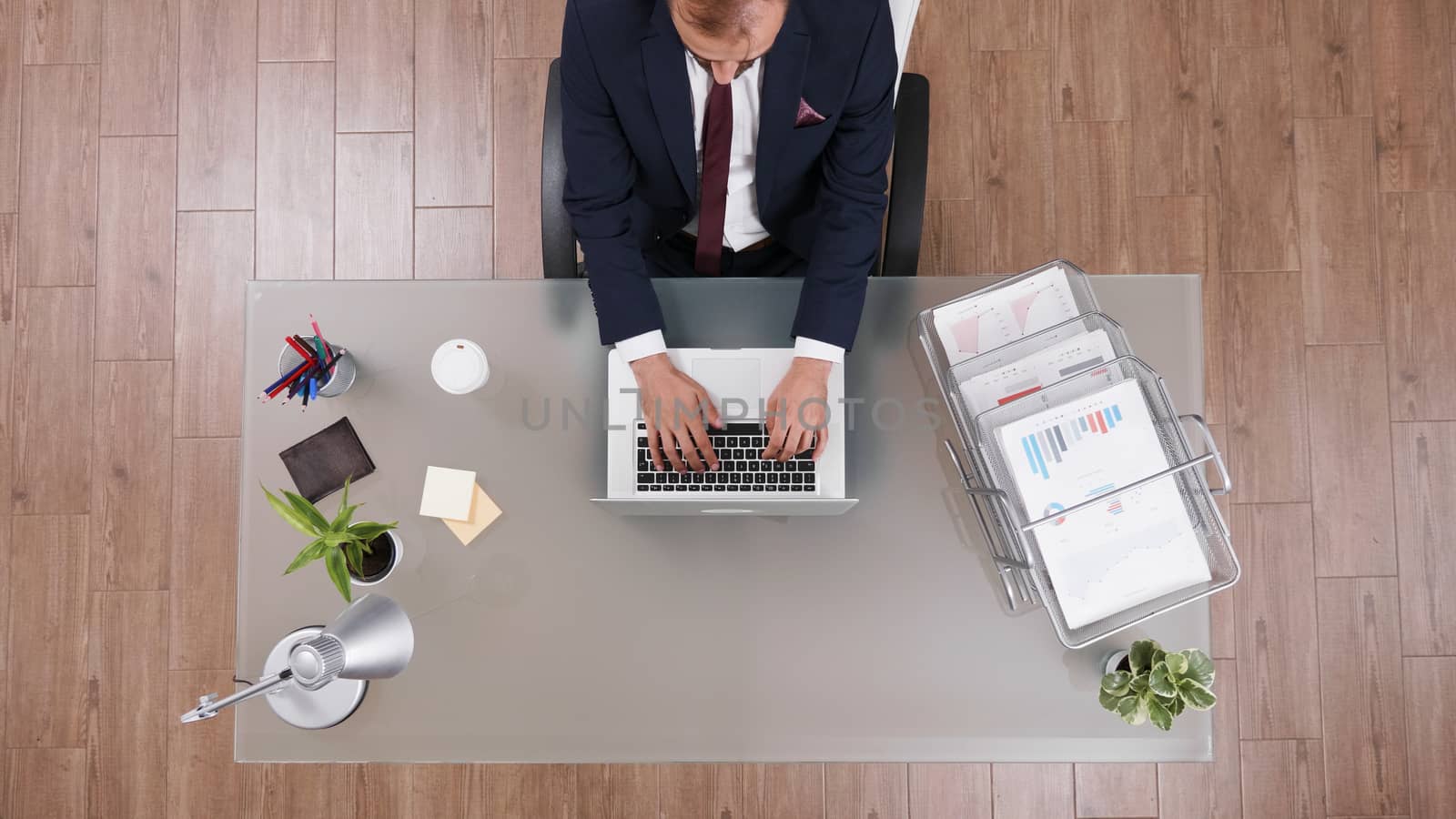Top view of businessman in suit typing on laptop with a cup of coffee next to him
