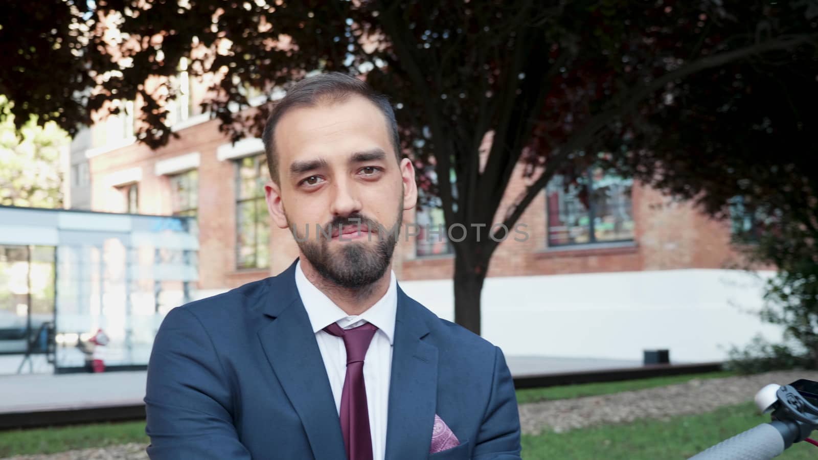 Yonug man in business suit looking at the camera and smiling. Slow motion outdoor portrait