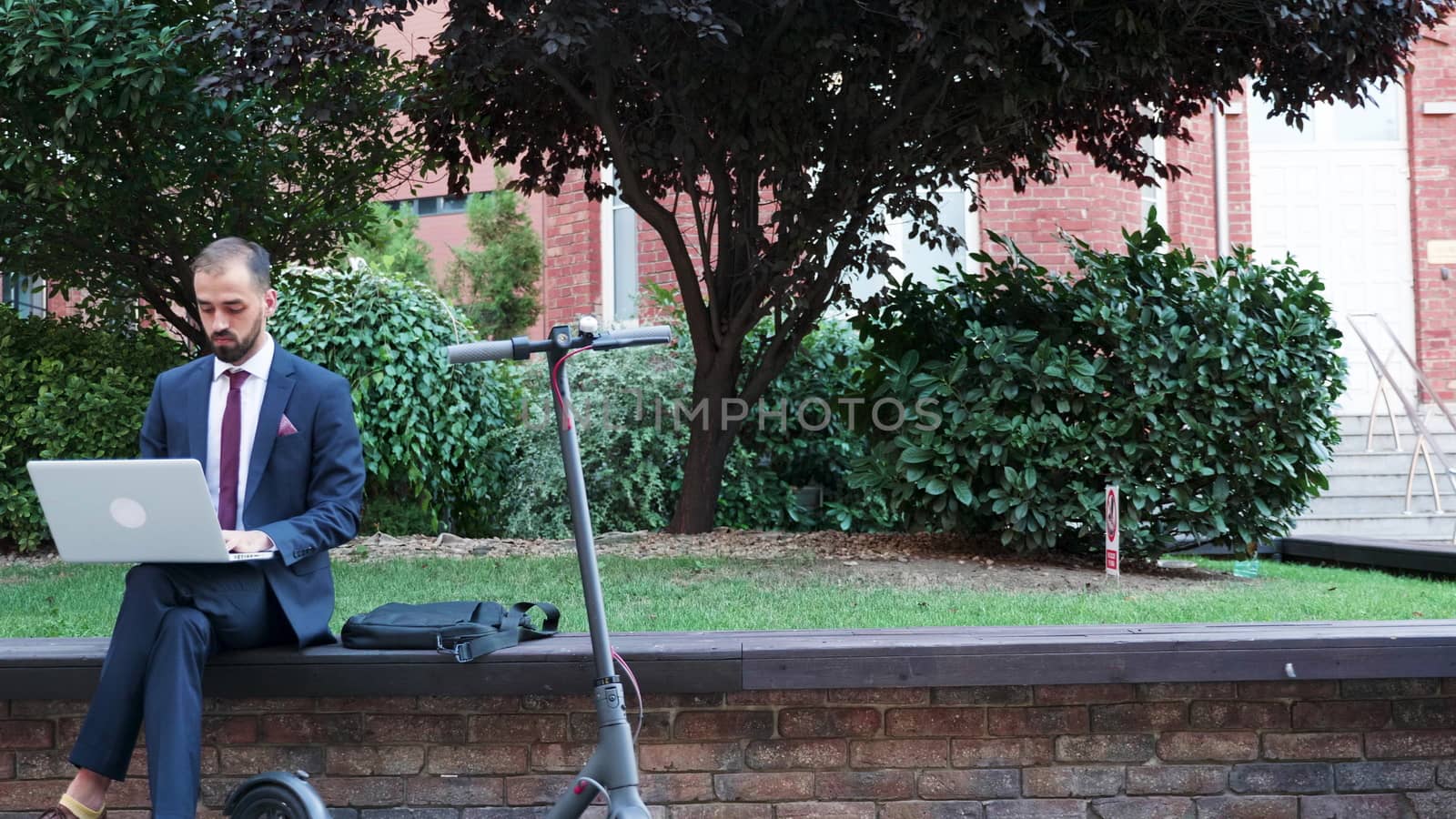 Young worker typing on the laptop outside of his office. Work on the go