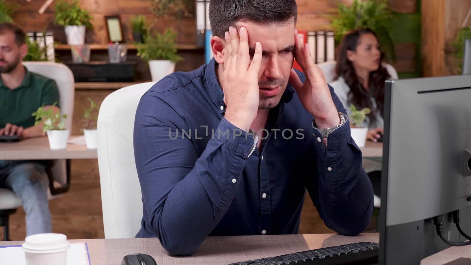 Portrait of stressed and overworked employee trying to work in a busy office