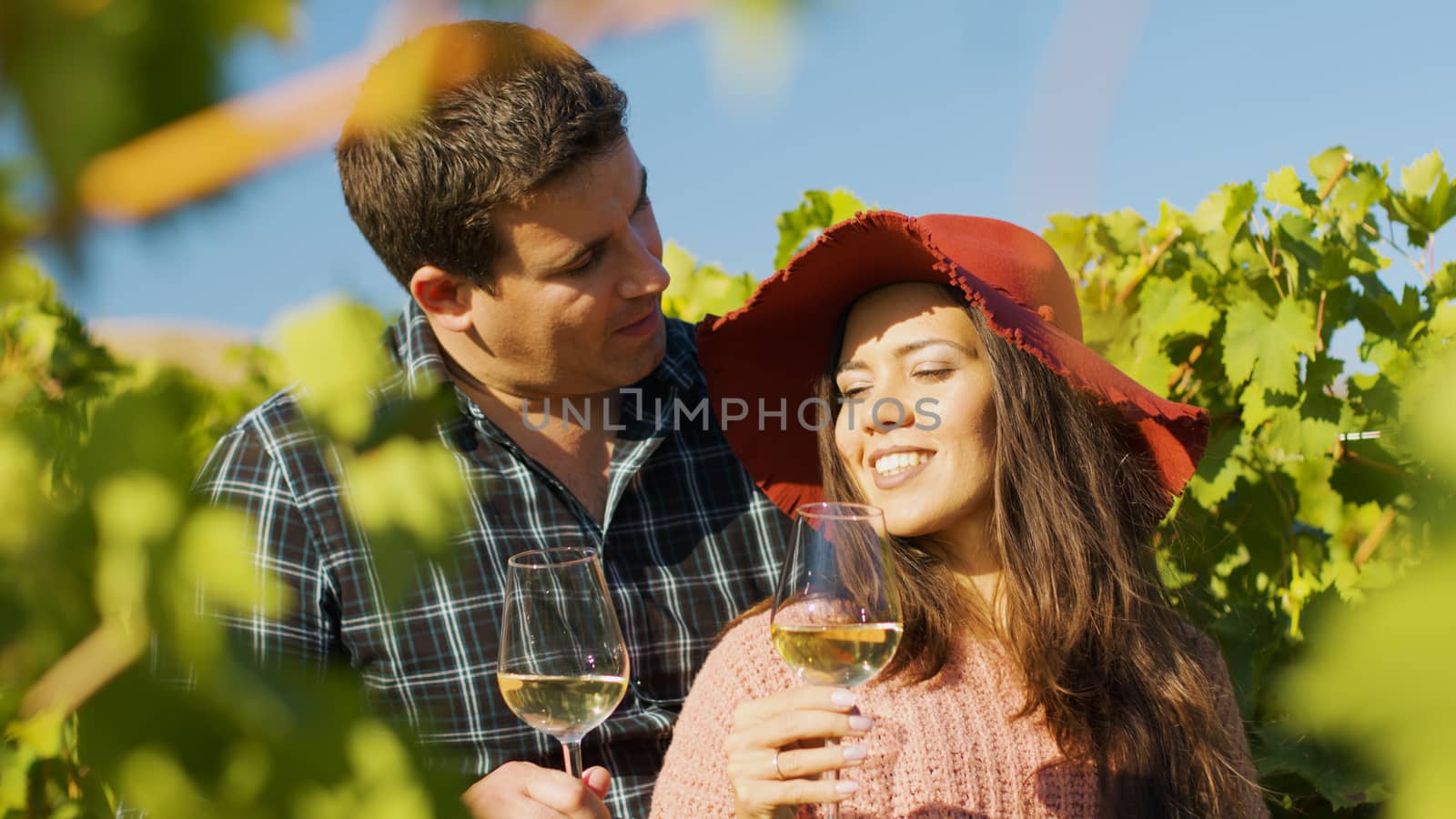 Close up of gorgeous couple embracing each other while holding glasses of wine in hands.