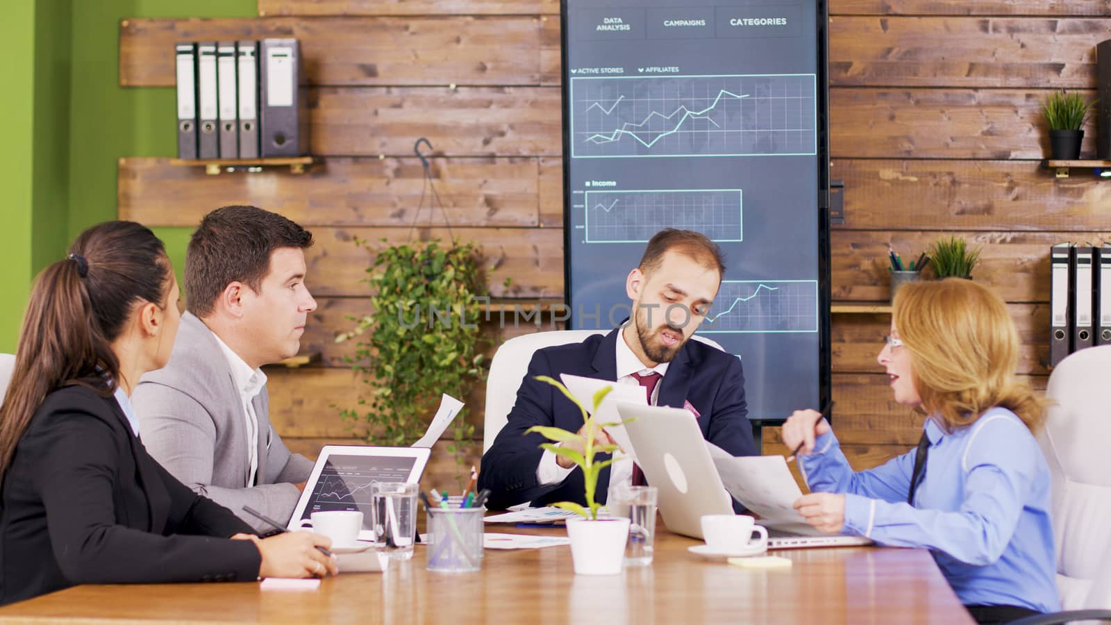 Corporate business meeting in modern meeting room with a vertical TV in the background