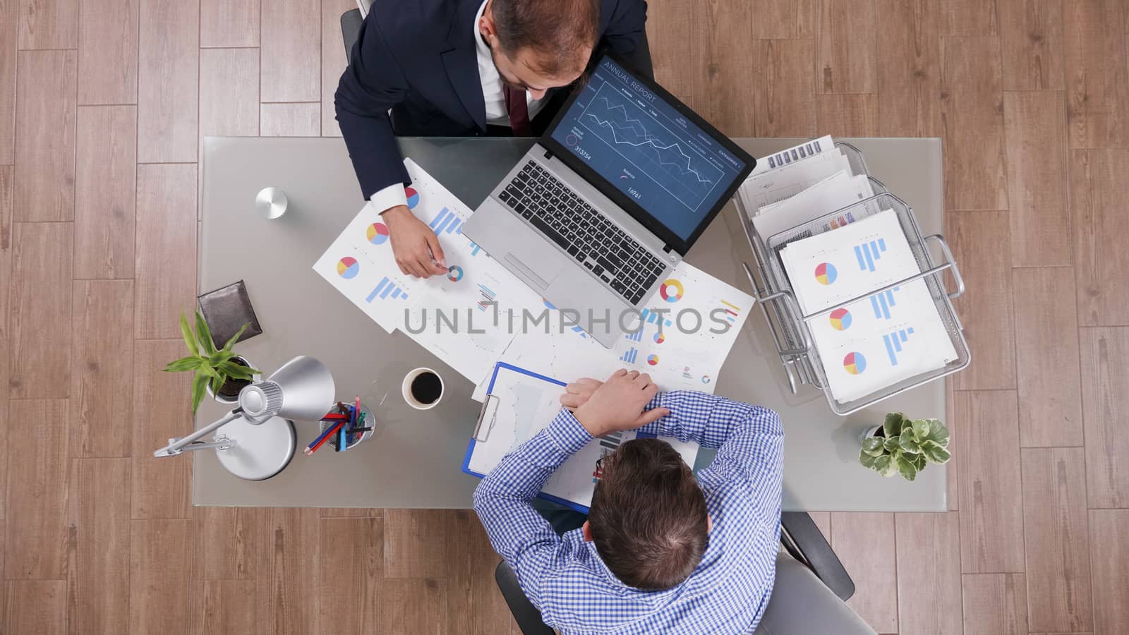 Businessmen working together at office desk and checking charts from laptop.