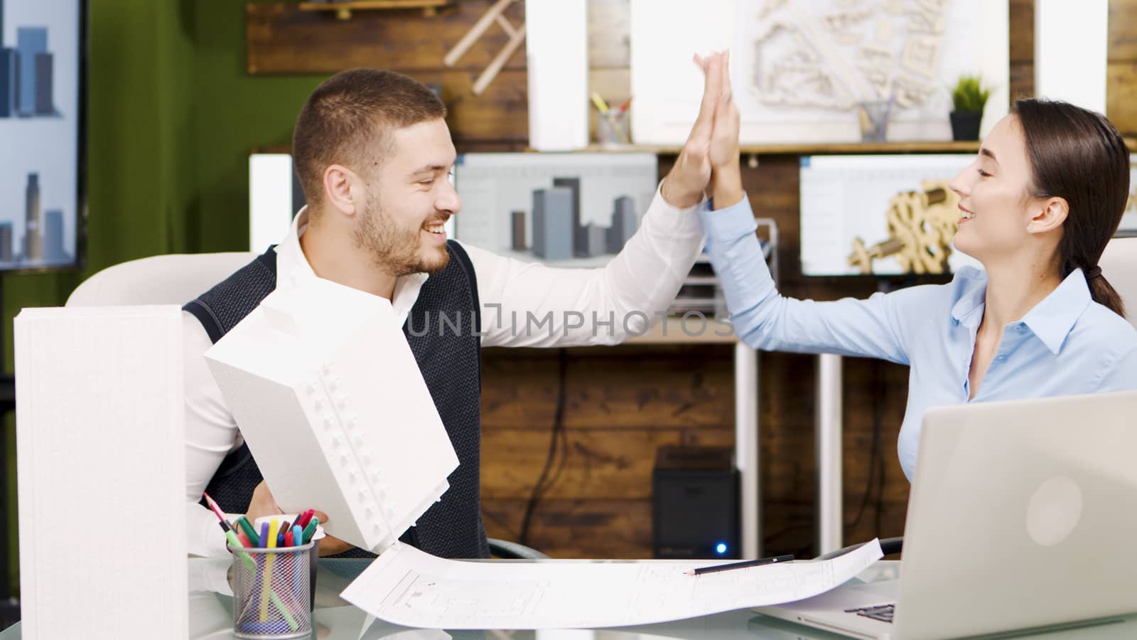 Happy young architect about their project and giving hi5 to each other. Successful architects.