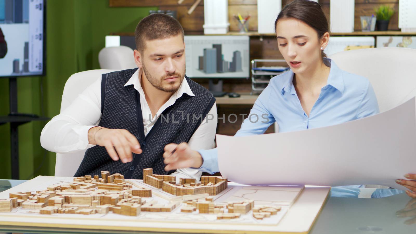 Team of architect holding blue print and working with building models for new town project.